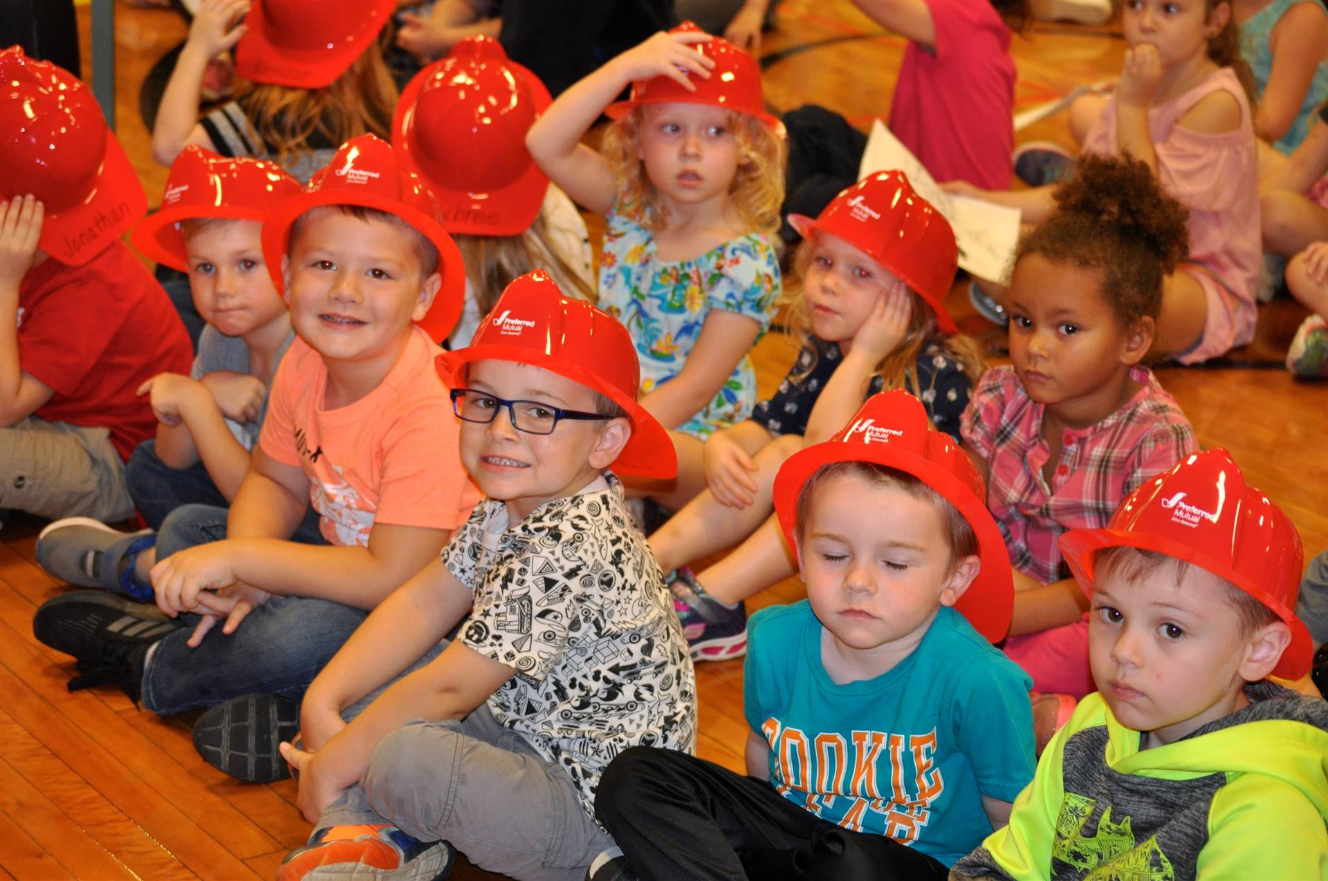 Students wear fire hats for fire safety assembly.