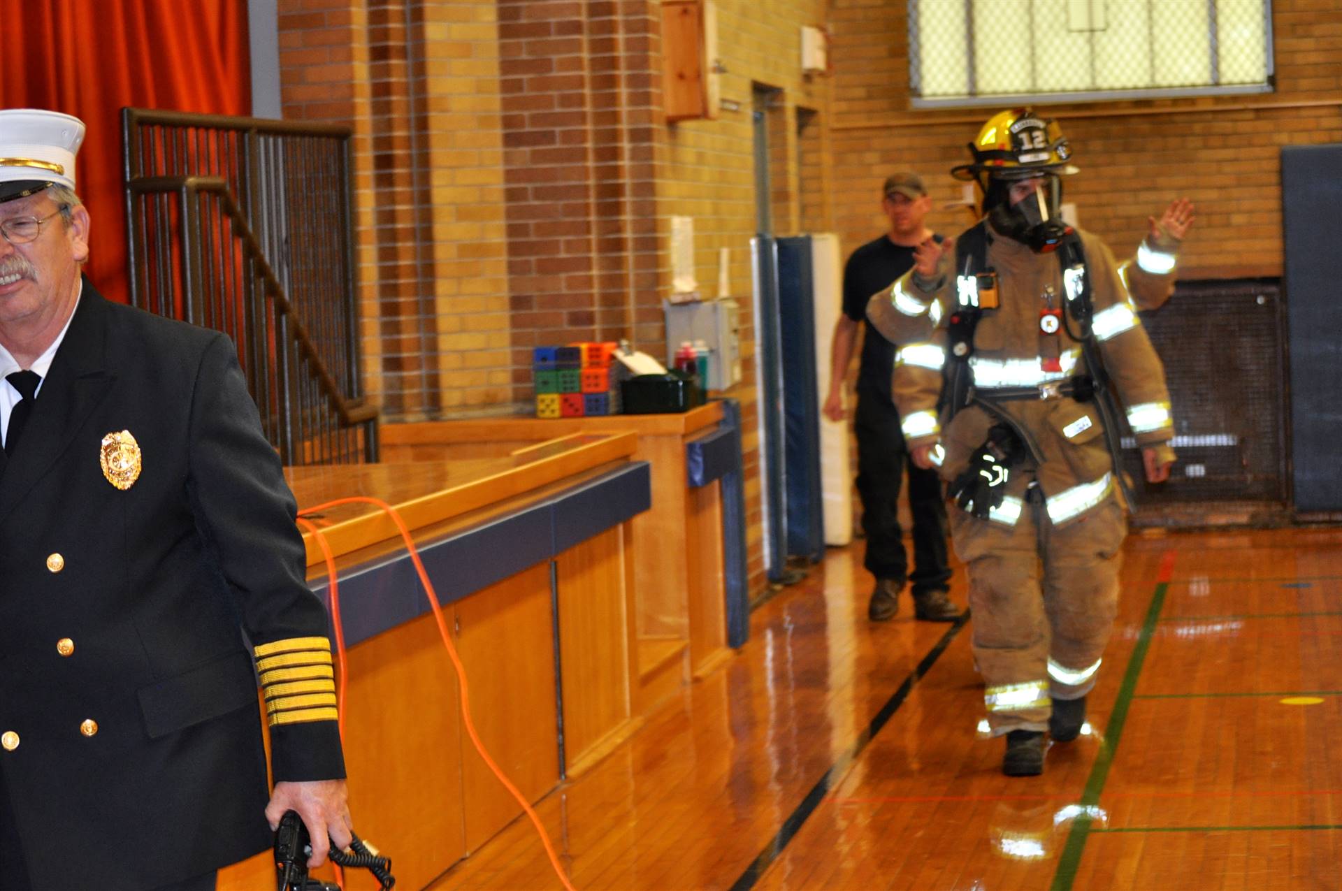 Firefighters enter gym for fire safety assembly.
