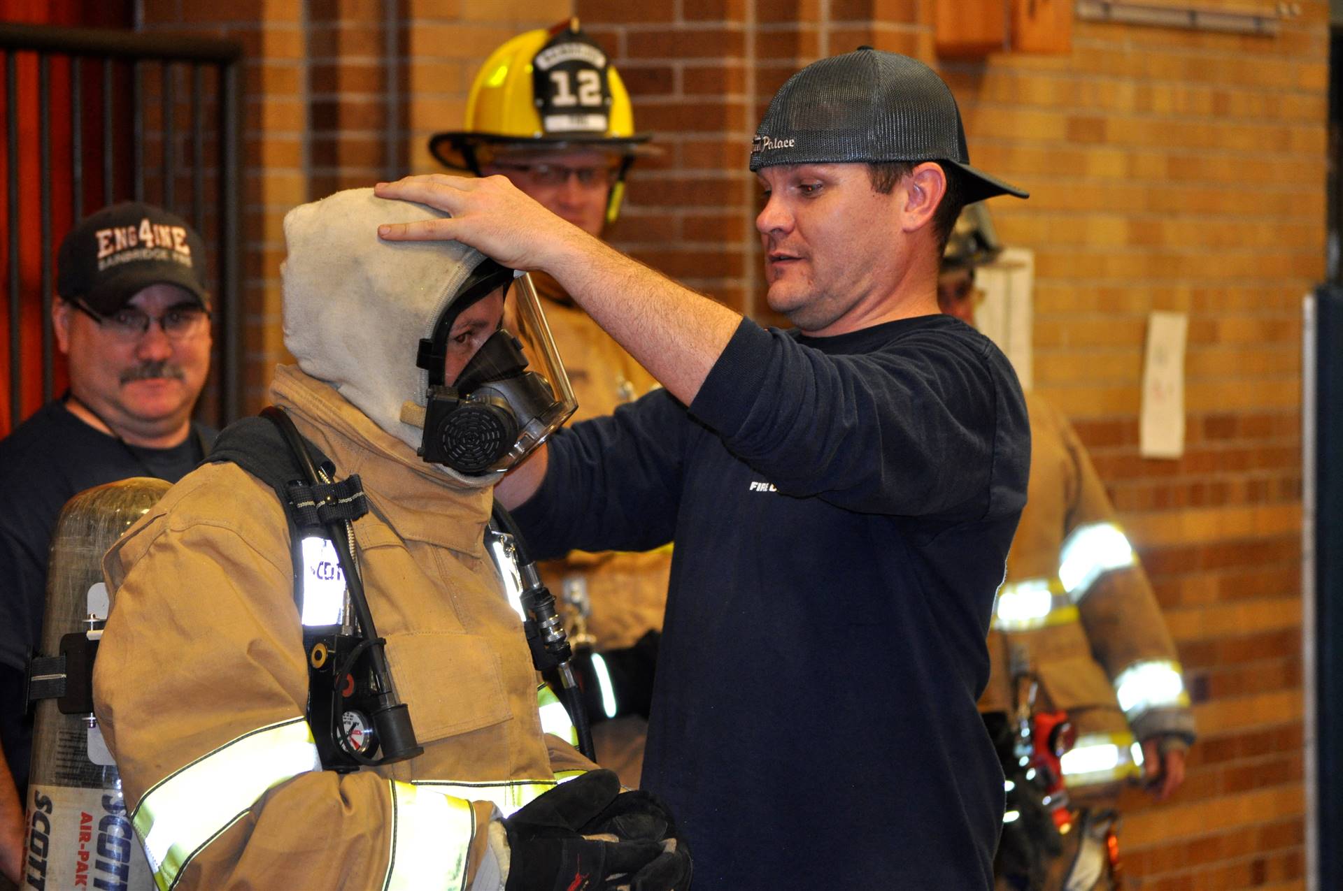 A firefighter helps a mystery staff member out of her costume.