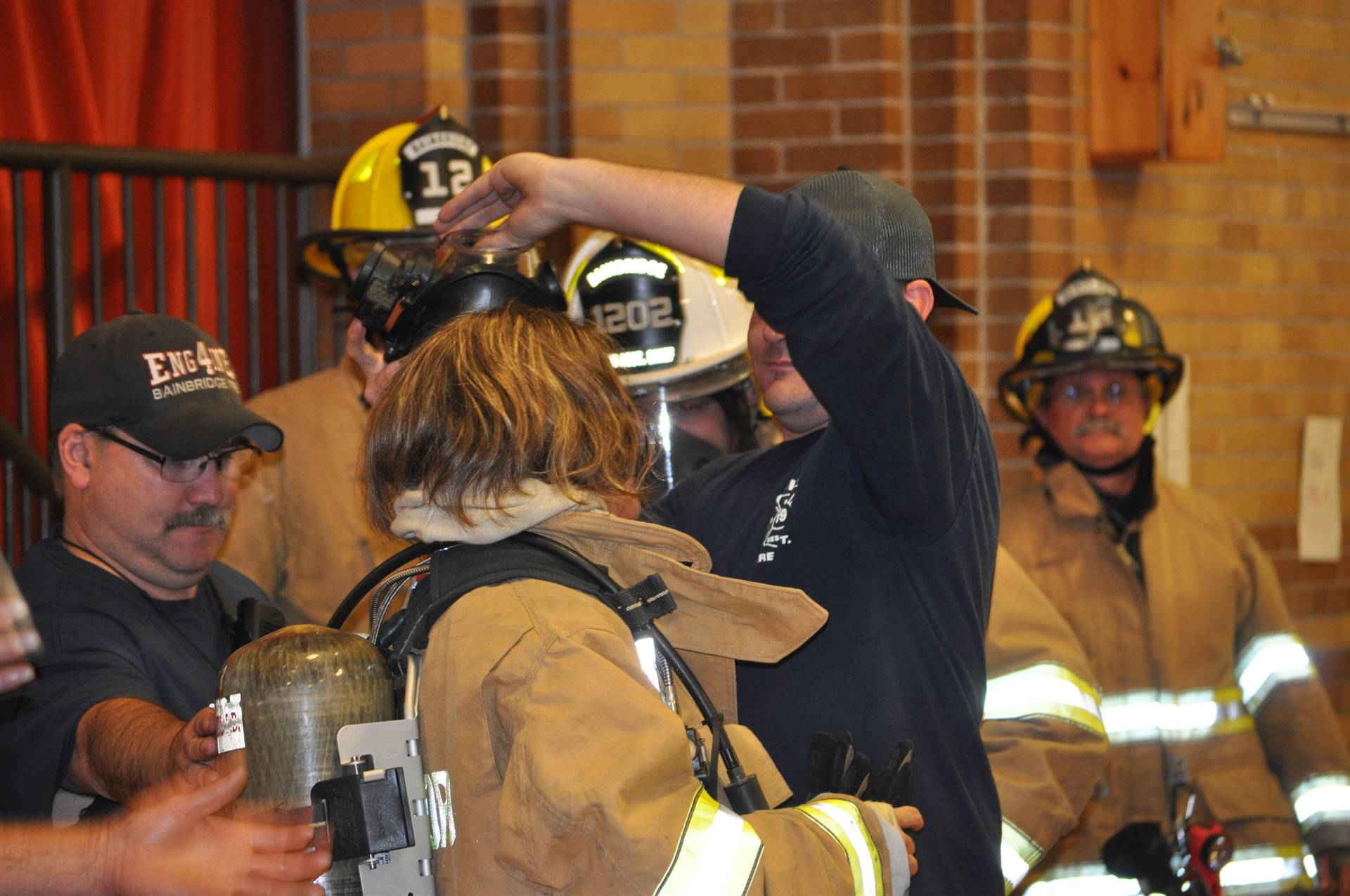 A firefighter helps a mystery staff member out of her costume.