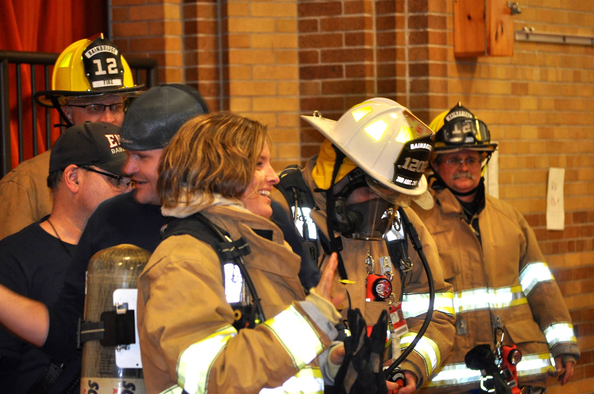 A firefighter helps a mystery staff member out of her costume.