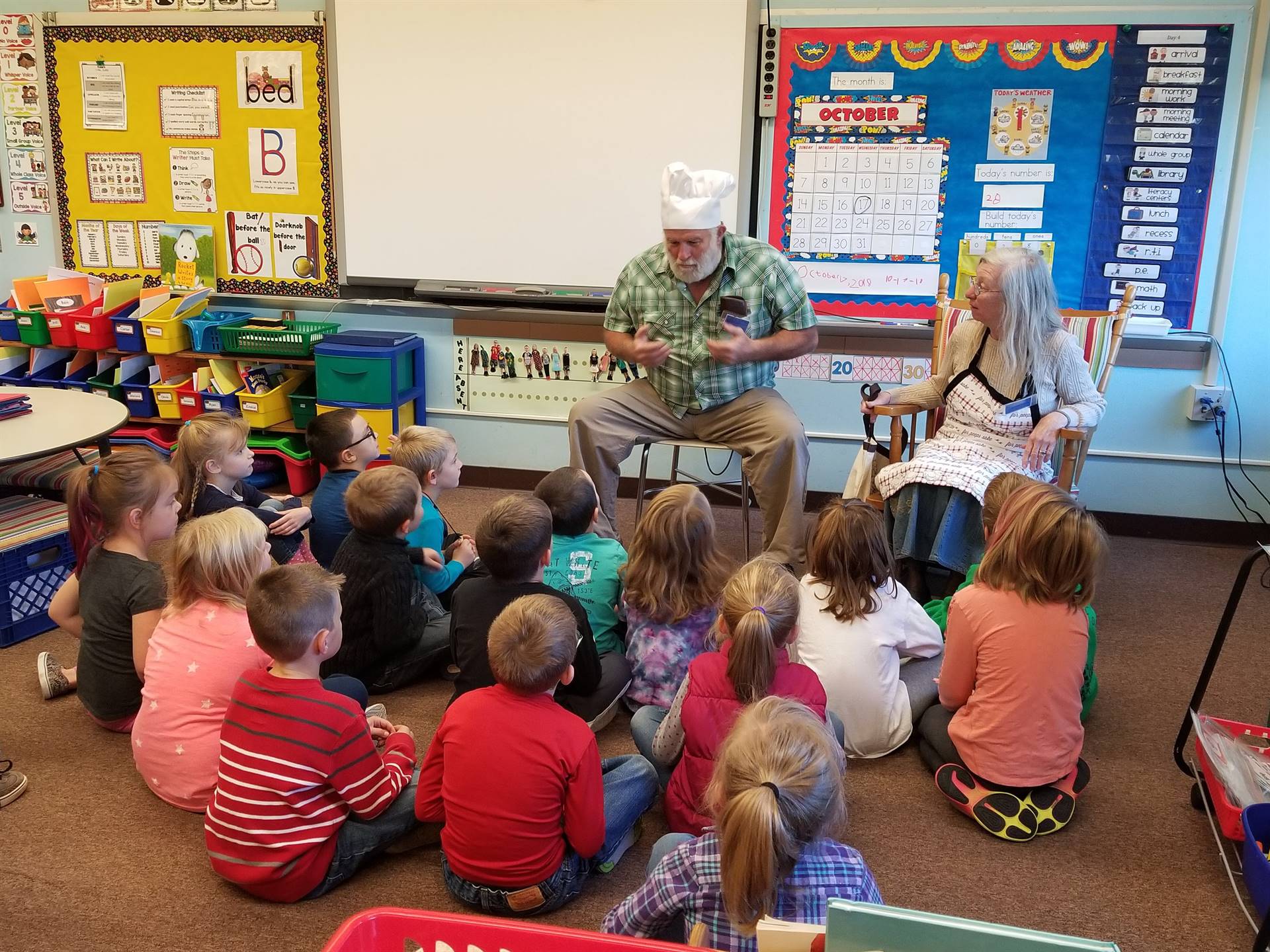 Mr. and Mrs. Wilcox read a story to a class.