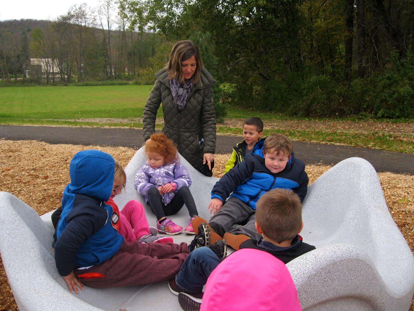 A teacher helps kids on the giant clam merry go round.