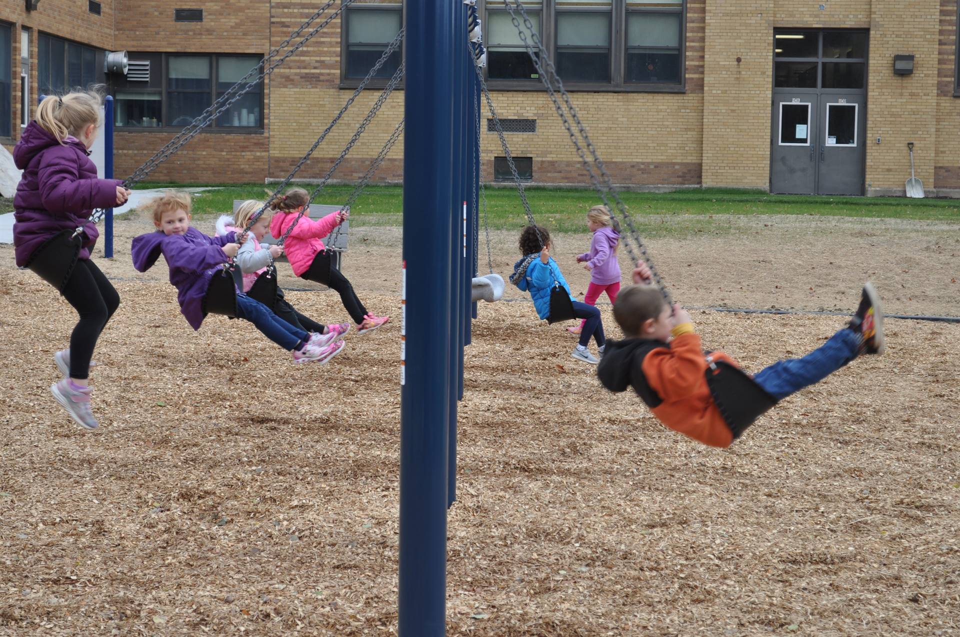 Students try swinging on the playground.