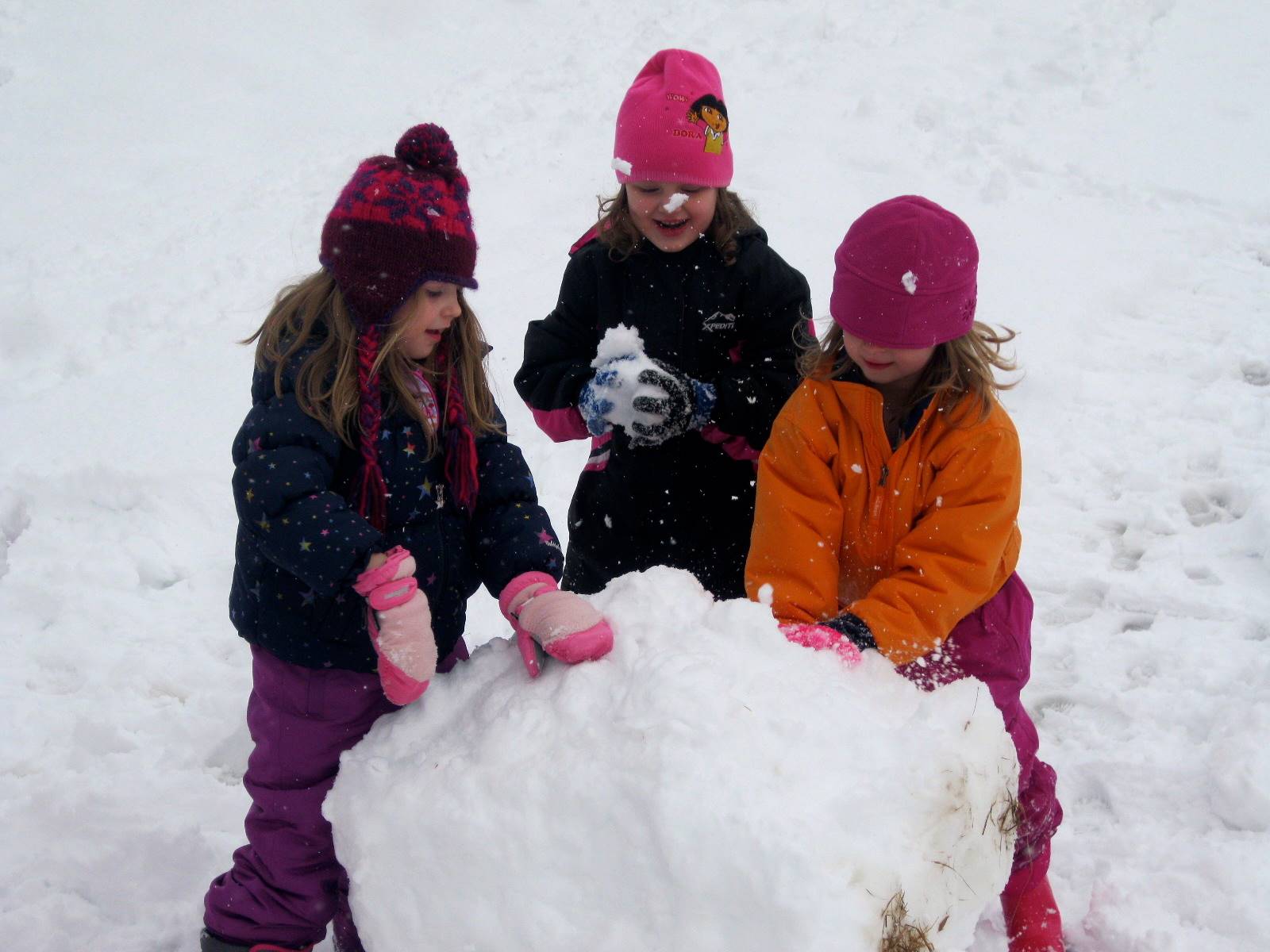 3 children building a snowman.