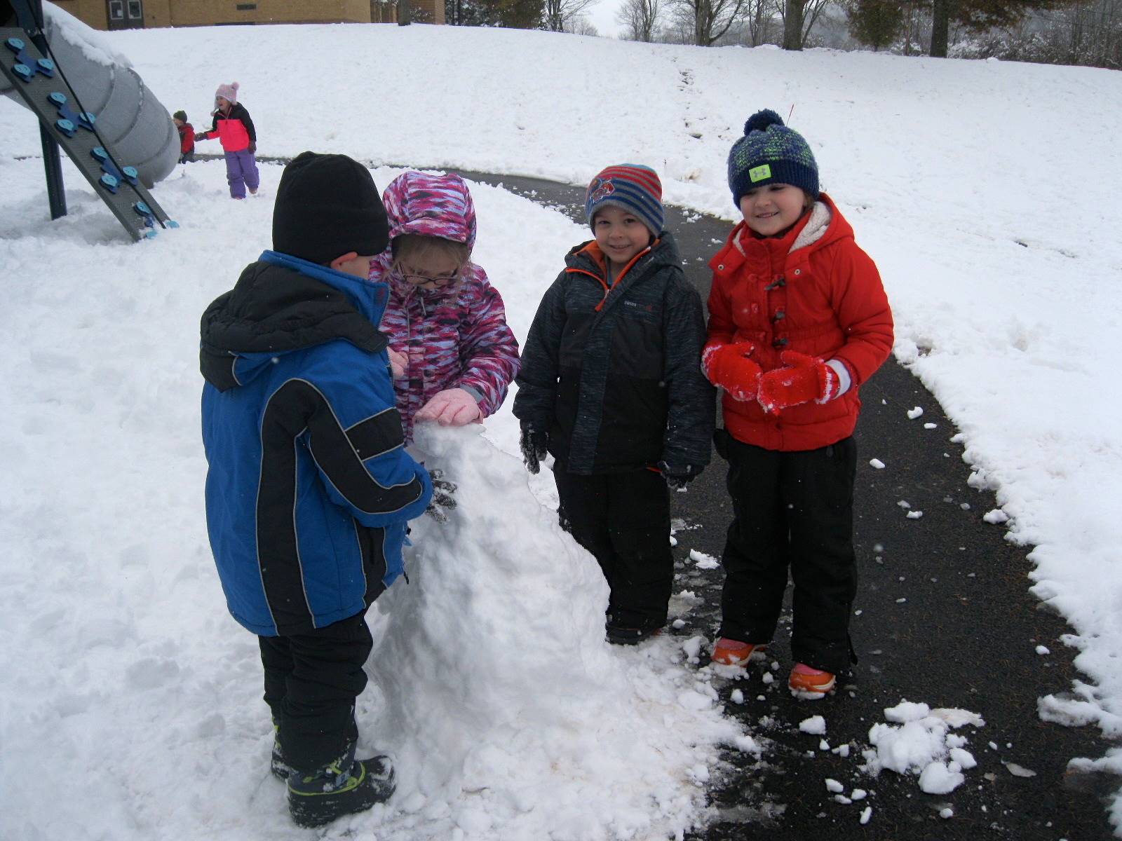 a group of children building a snowman.