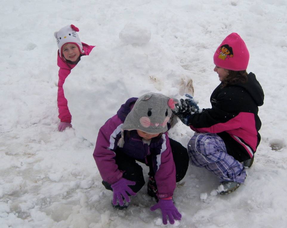 3 children building a snowman.