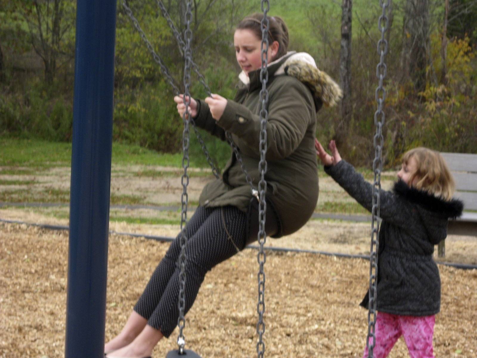 A student pushes her teacher on swing.