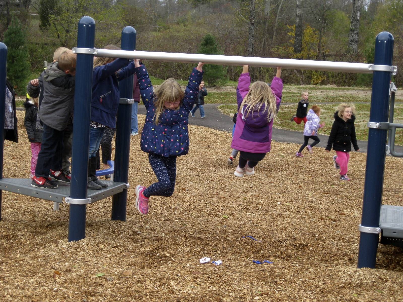 2 students are hanging on monkey bars.