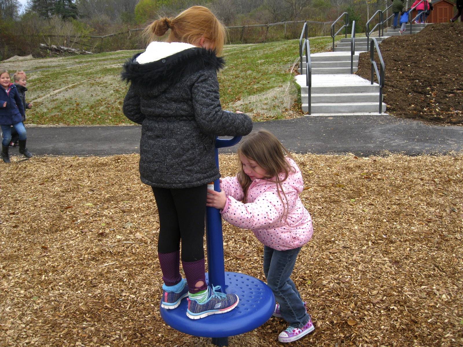 Cooperation! 1 student twirls another on the playground.