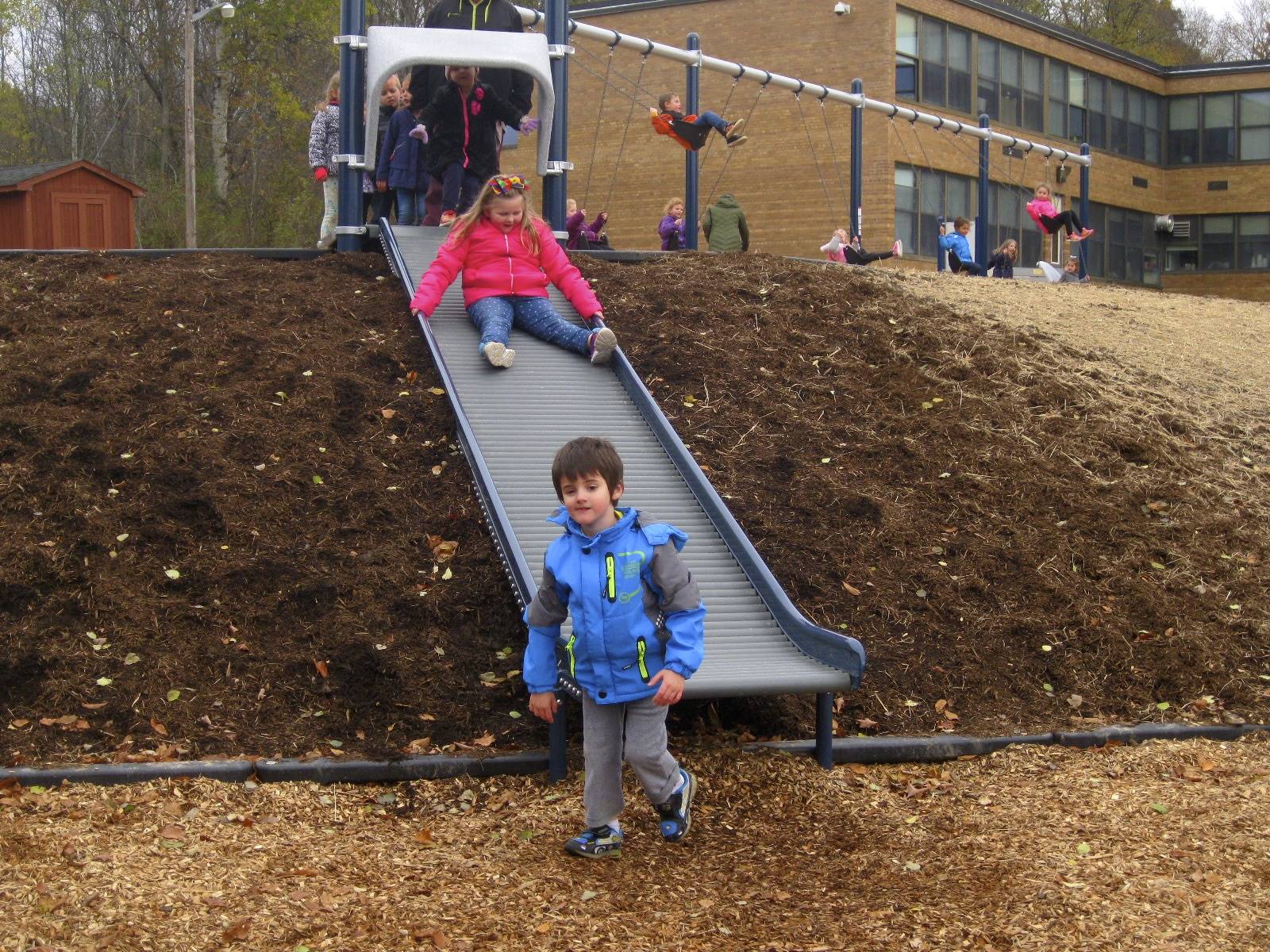 2 students sliding down roller slide.