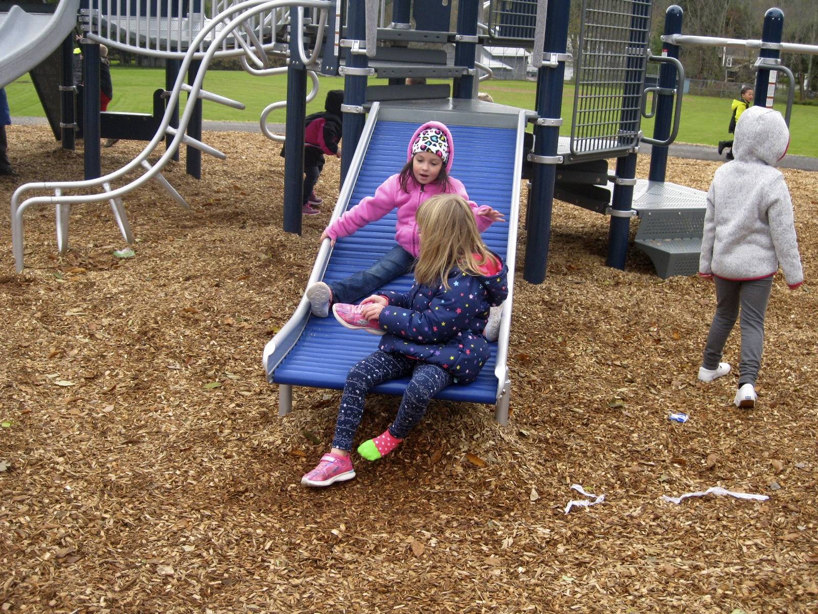 2 students slide on roller slide.