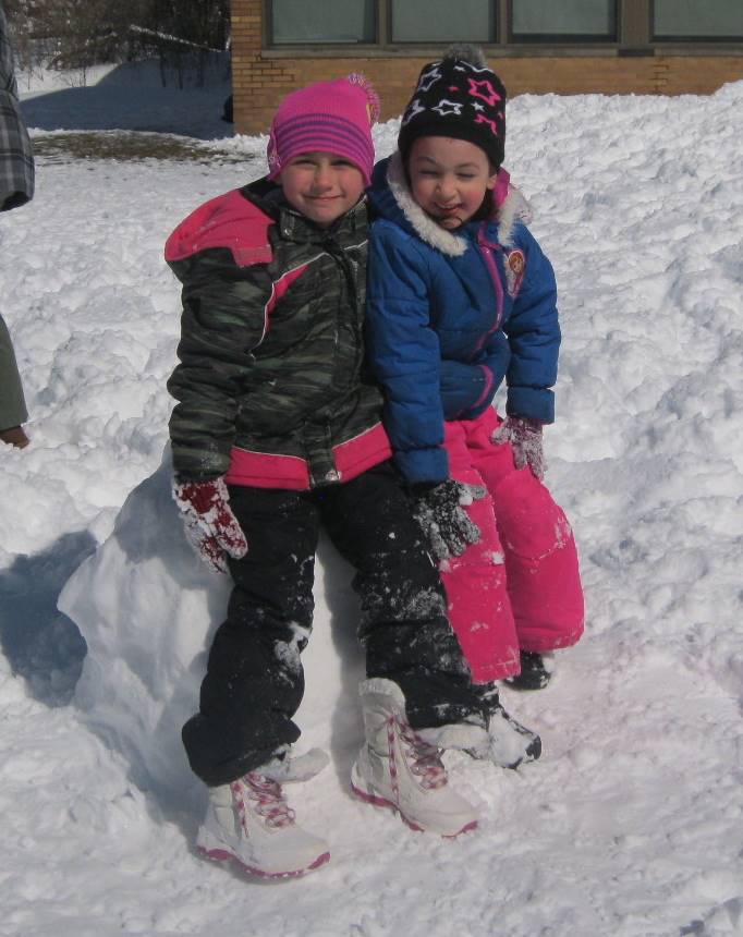 Children perched on a  snowball.