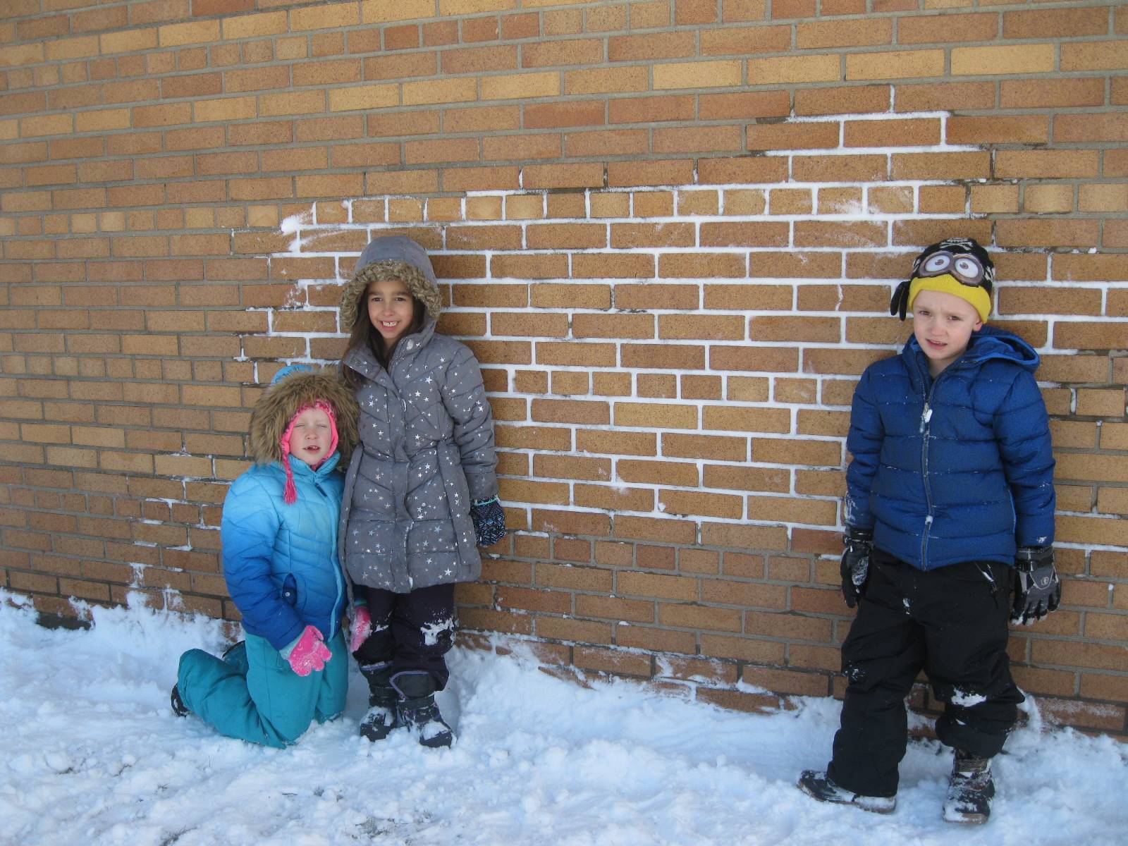 Children use snow as "chalk" to decorate building.