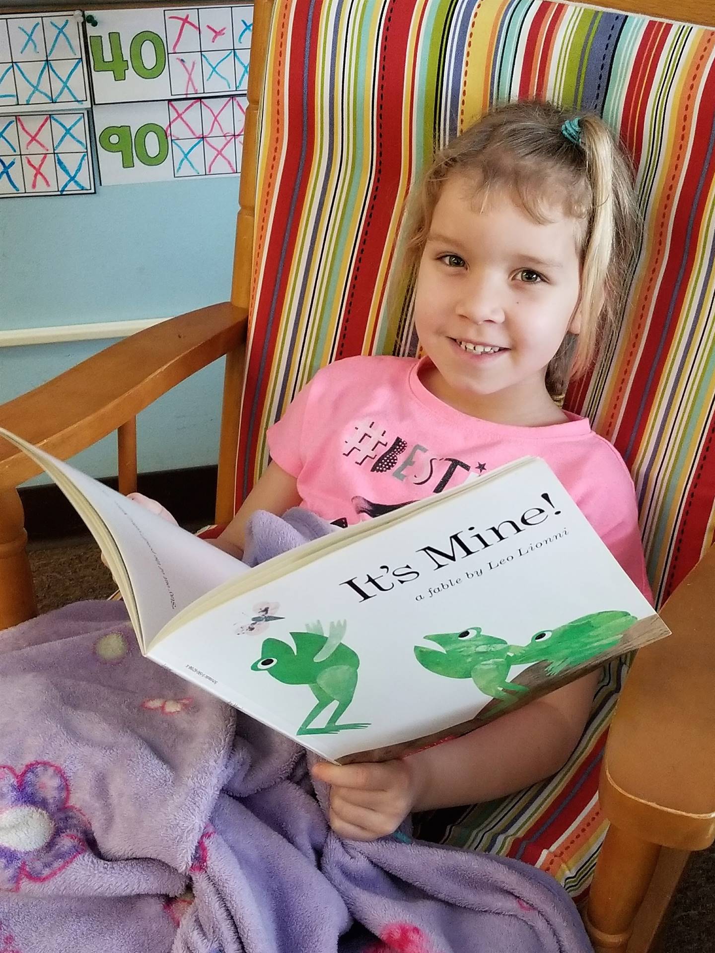 first grader reads happily in a rocking chair!