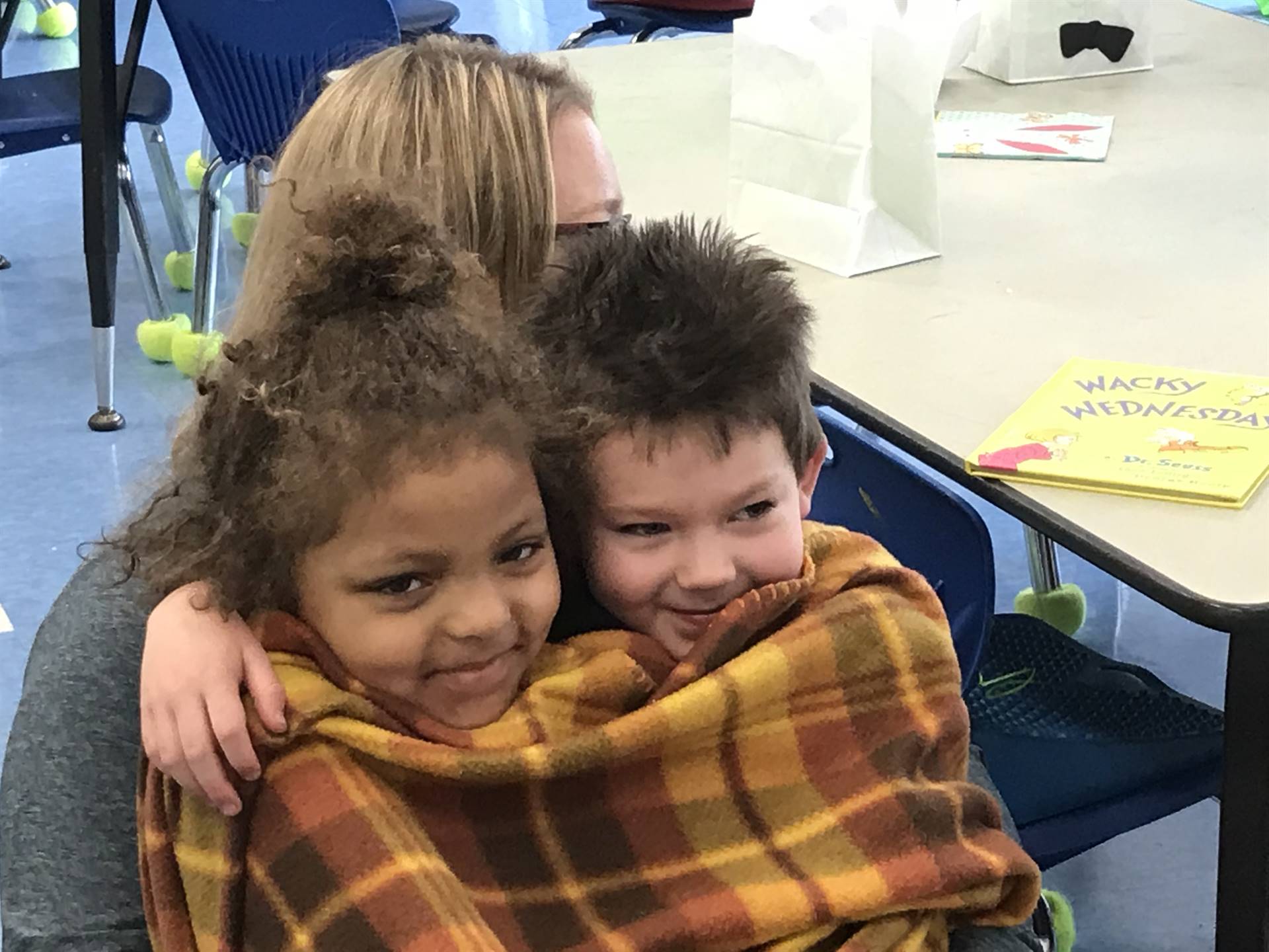 2 Kindergartners snuggle up to listen to a story.