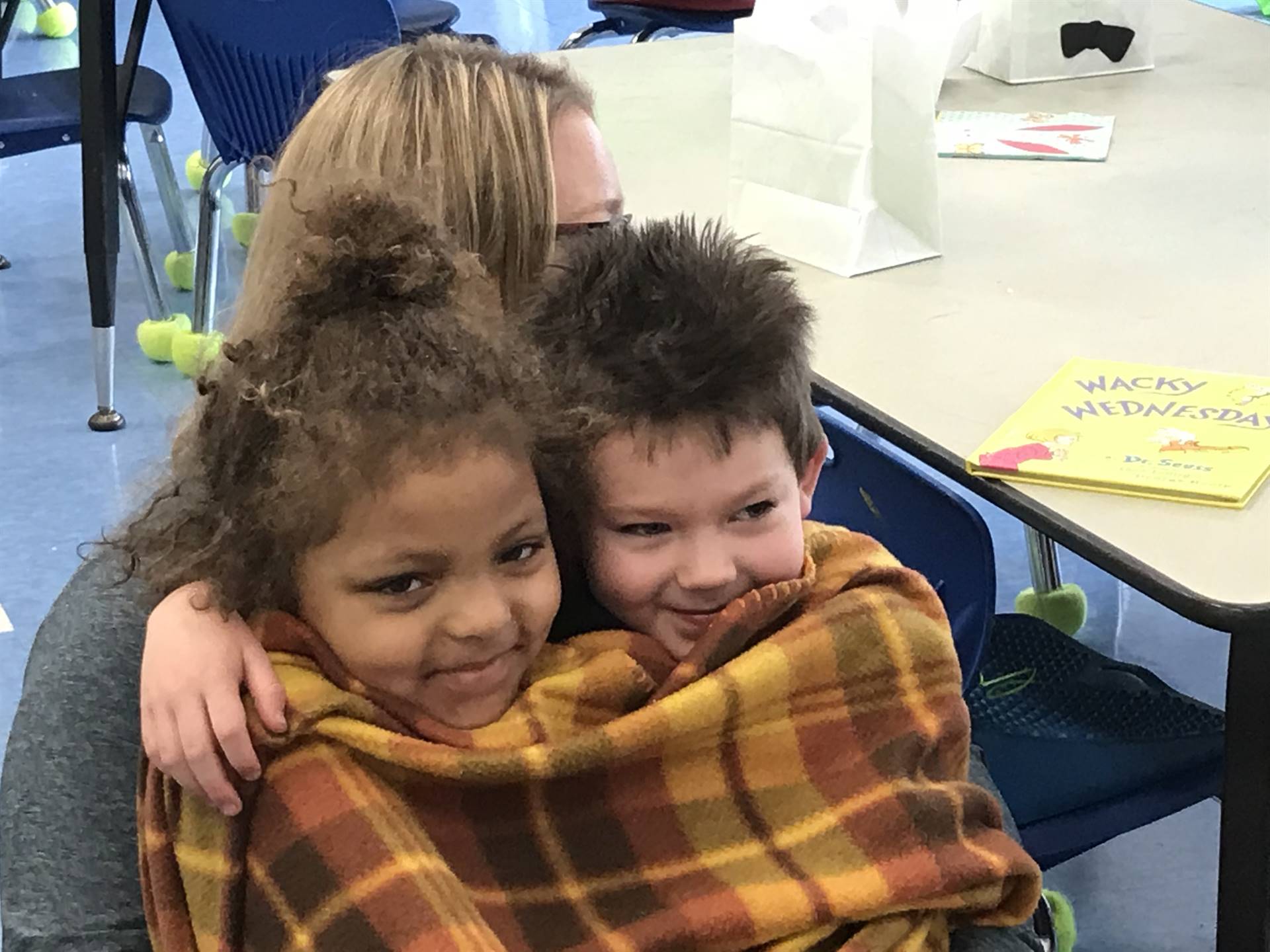 2 Kindergartners snuggle up to listen to a story.