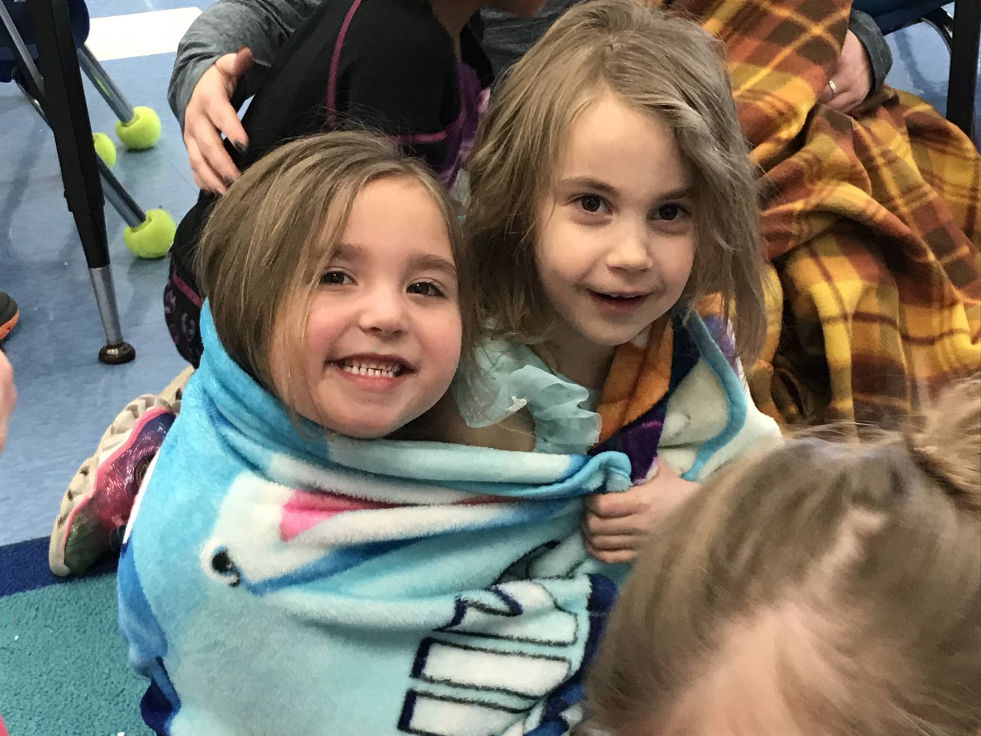 2 Kindergartners snuggle up to listen to a story.