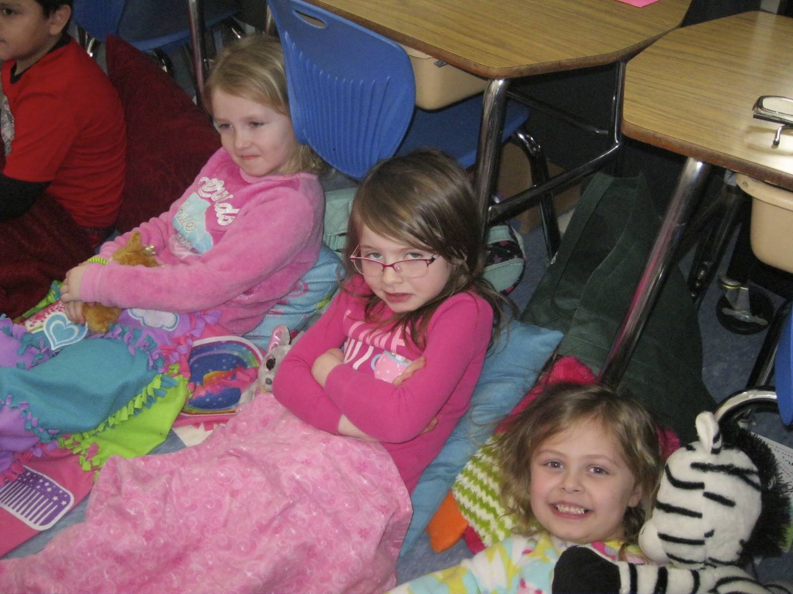 Three Students cozy up together to listen to a book.