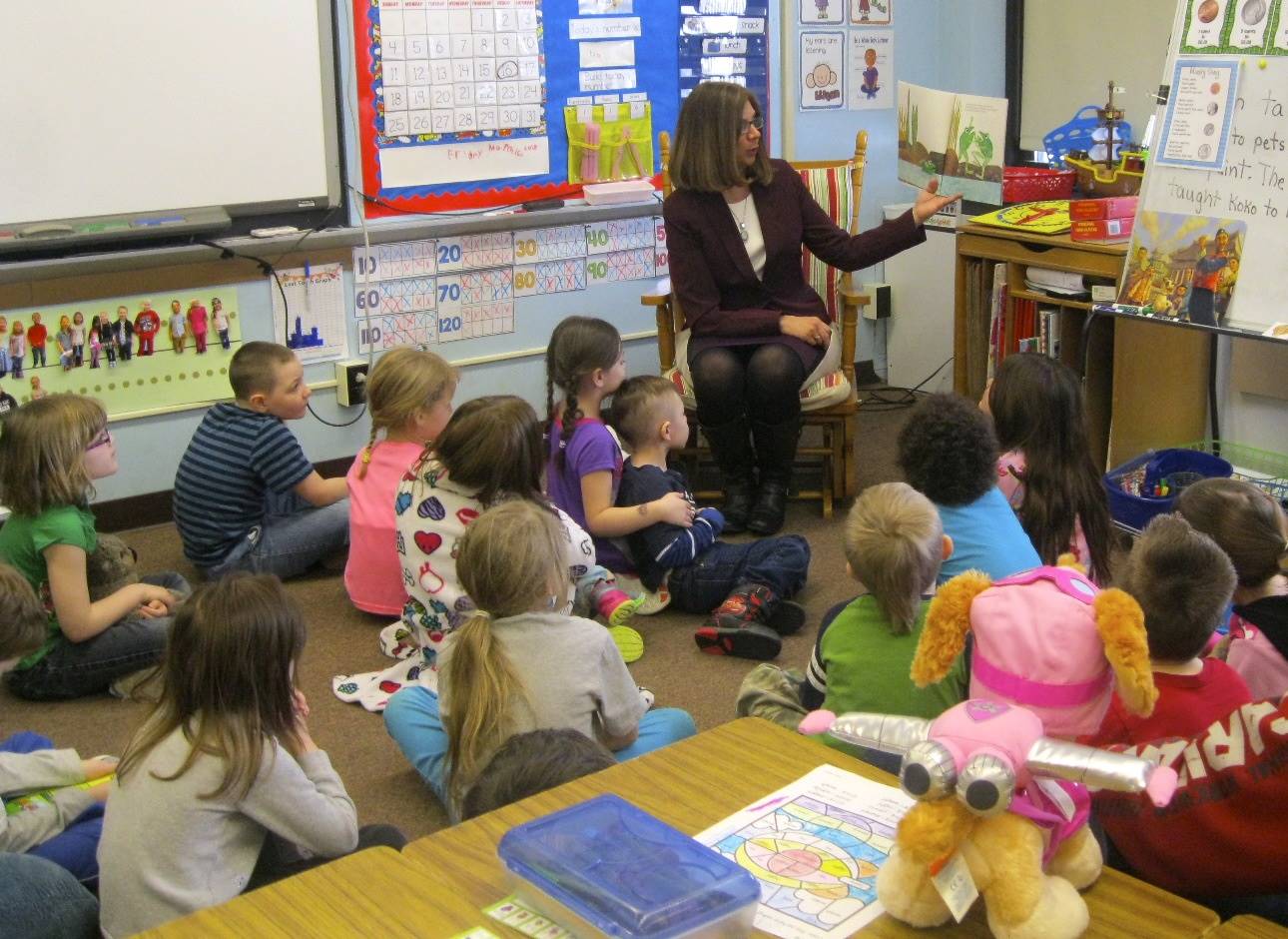 three Students cozy up together to listen to a book.