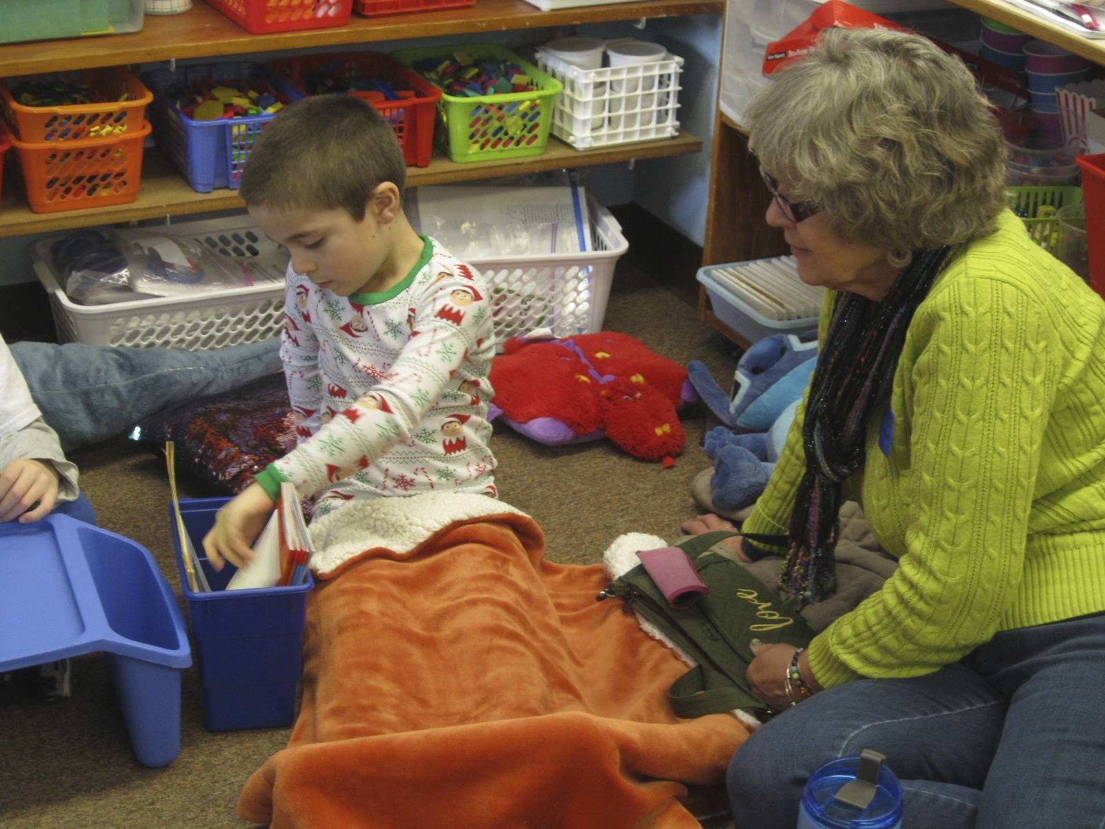 A student and his grandma snuggled together with a book.