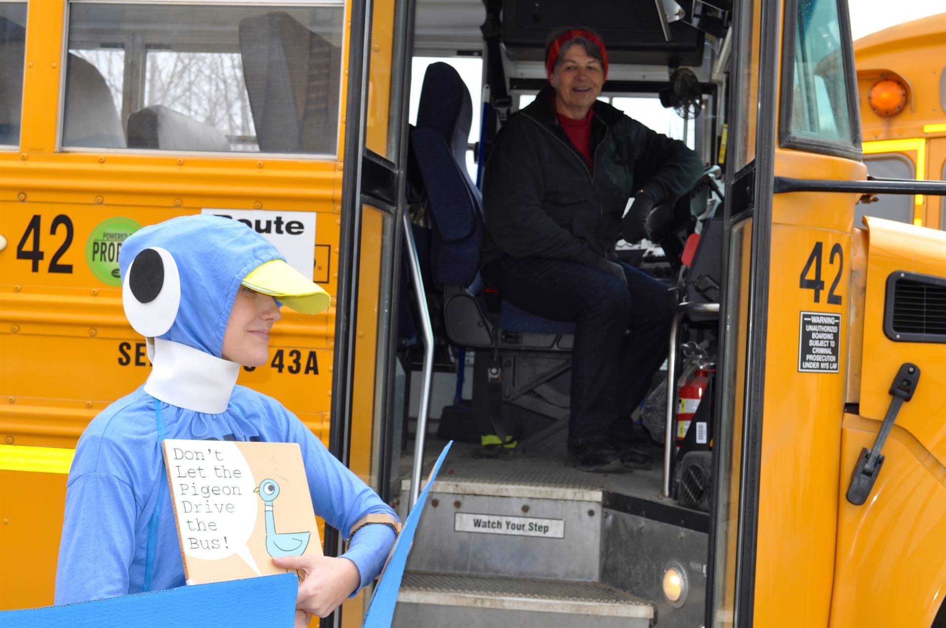 Teacher dressed up like a pigeon standing by the bus.