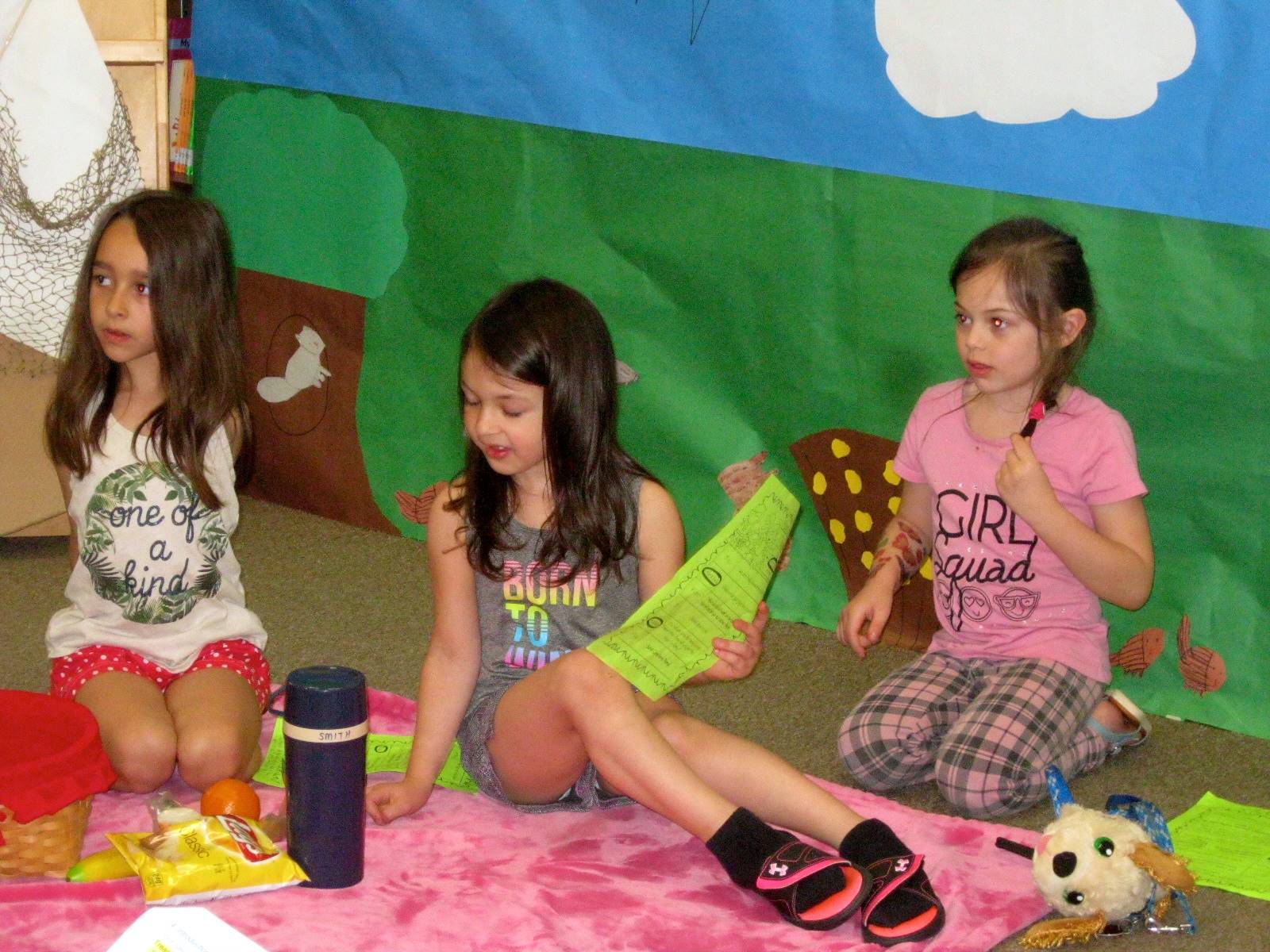 3 first graders show what items to bring for a picnic.