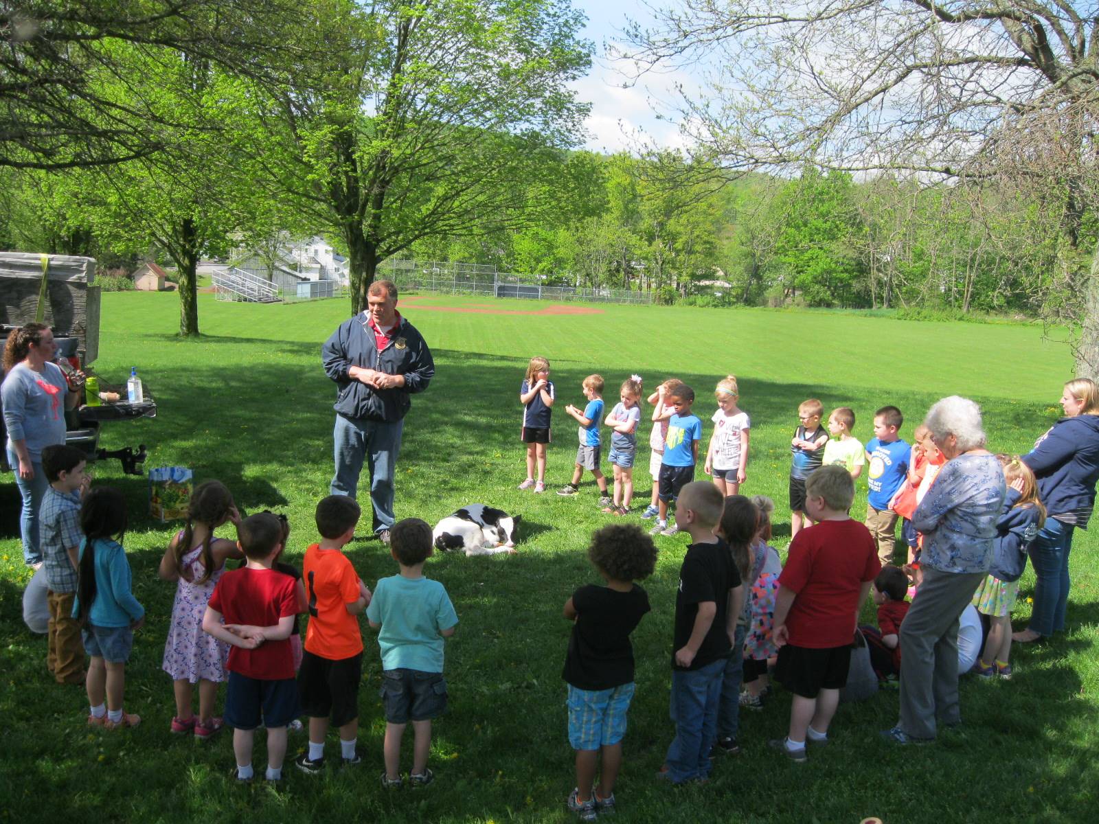 kindergartners listen to a man talk about  a calf