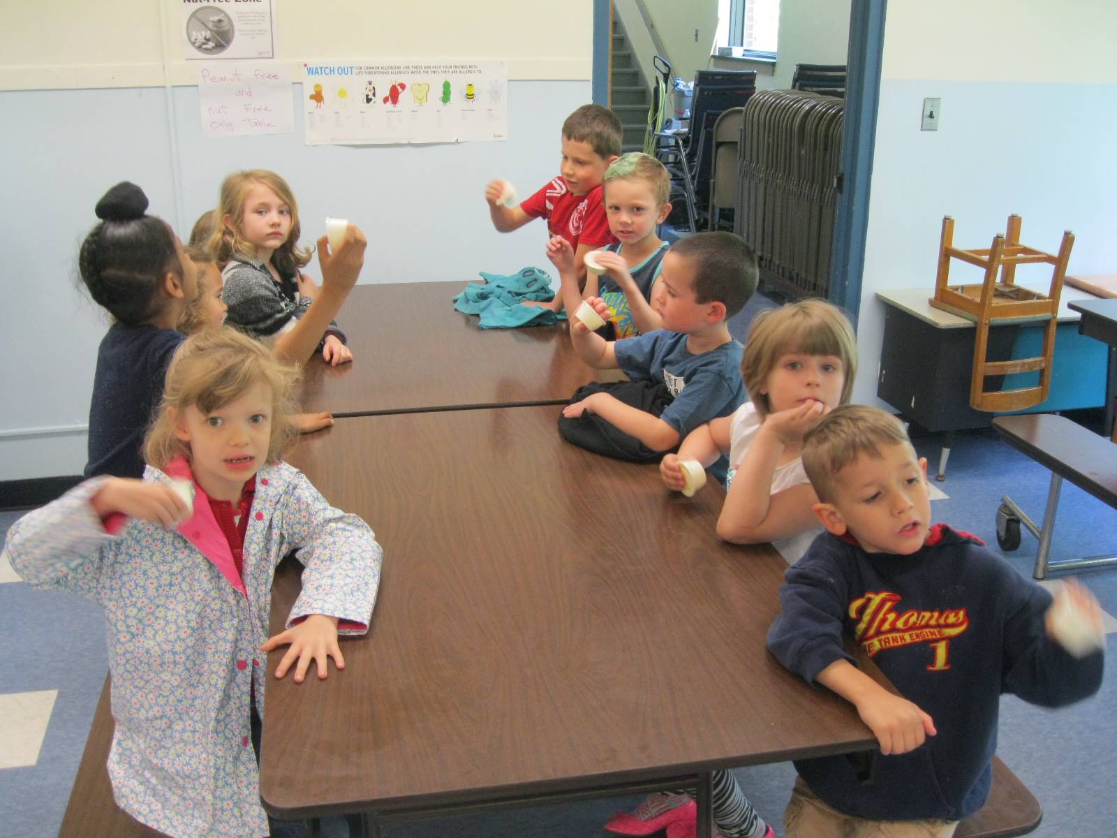 Kindergarten students shake cream to make butter.