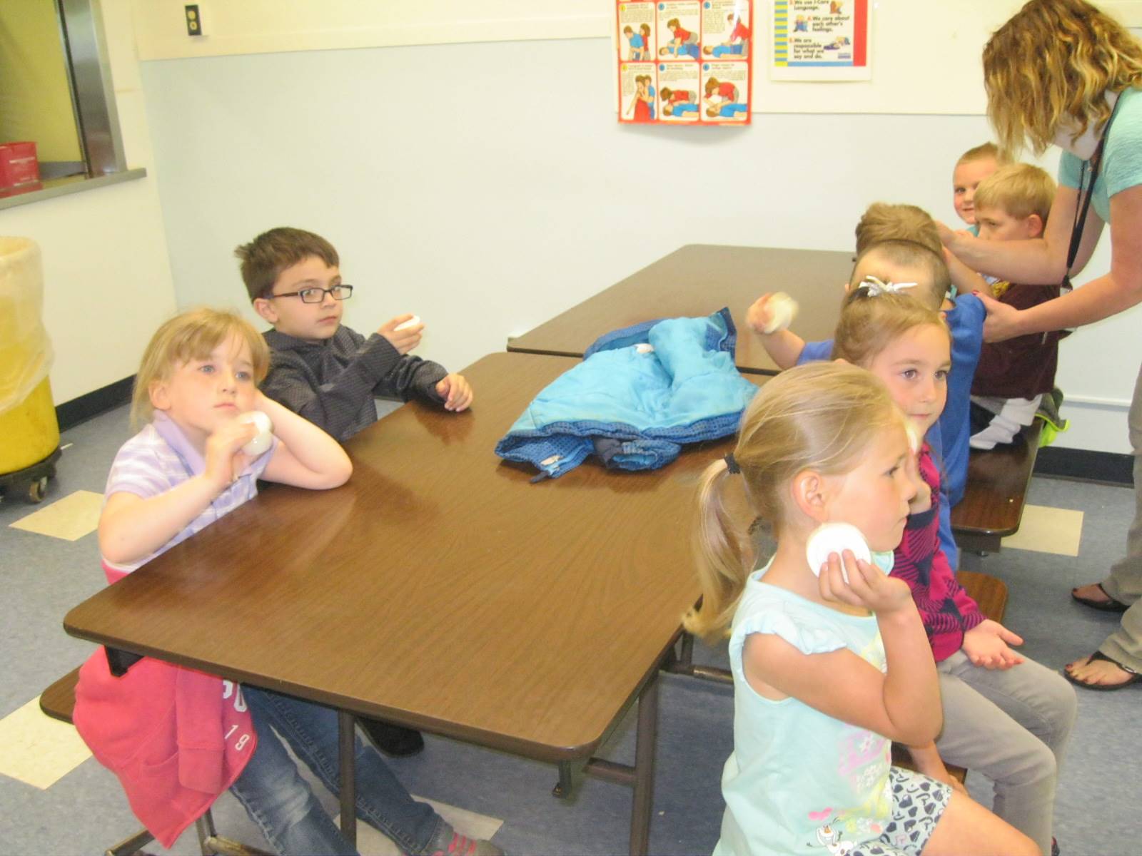 Kindergarten students shake cream to make butter.