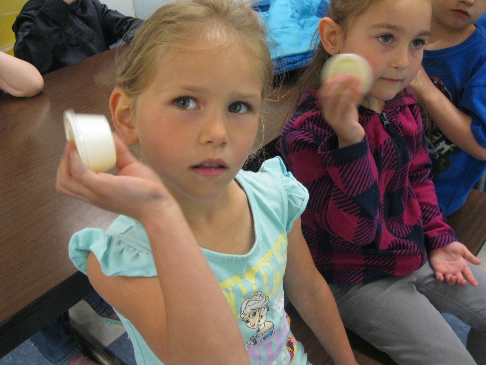 Kindergarten students shake cream to make butter.