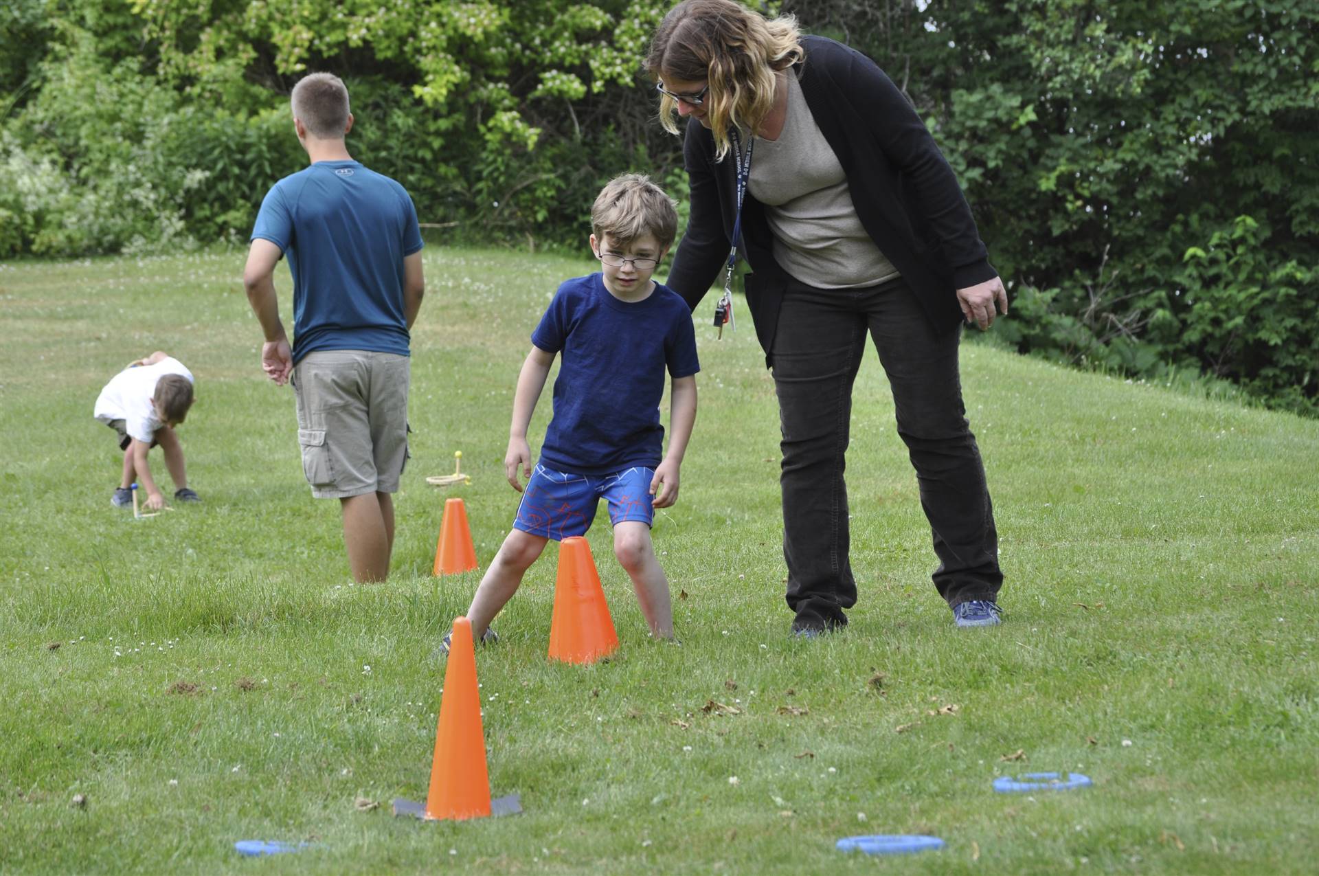 Adult assists student during game station at campout.