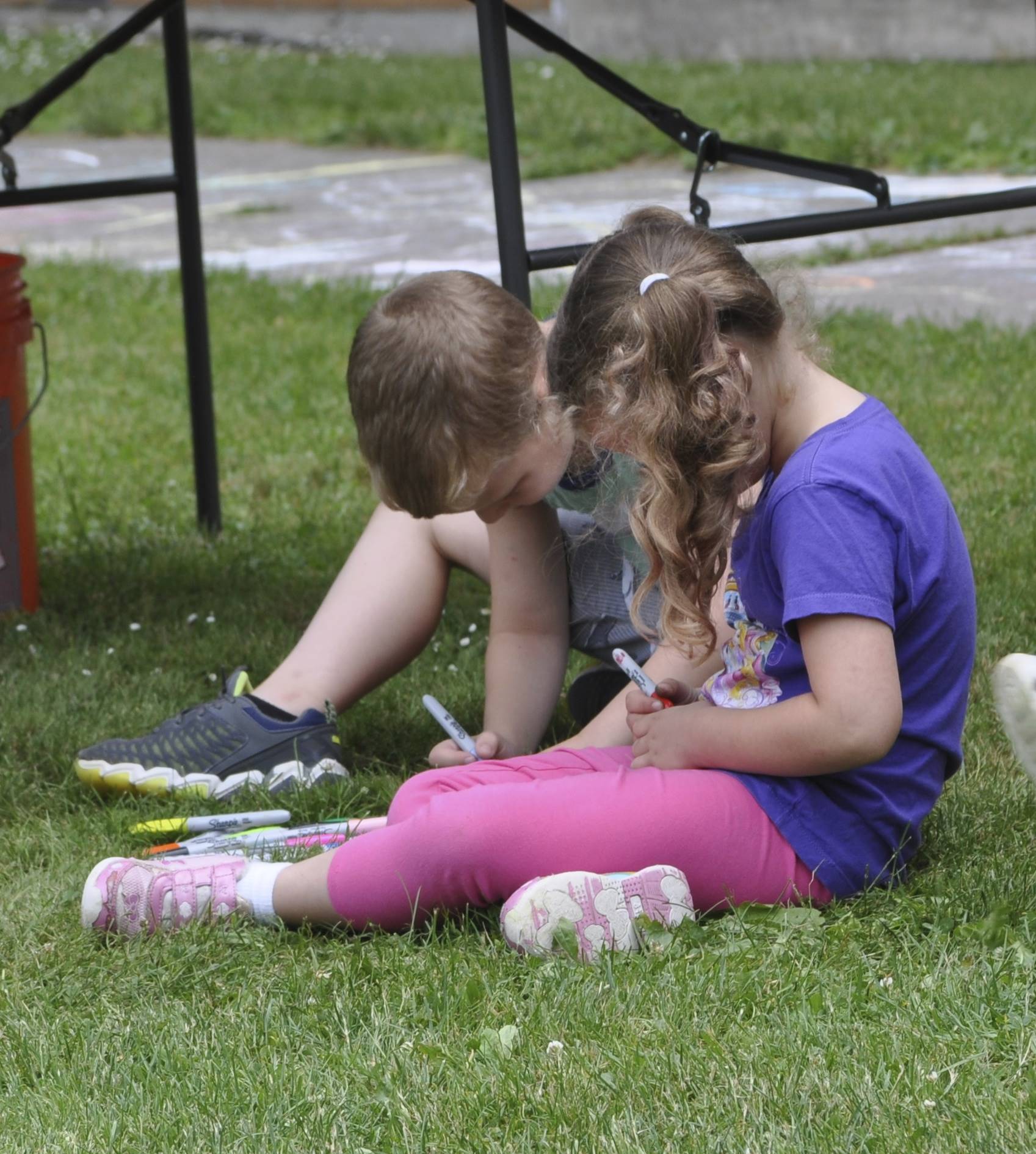 2 students decorate rocks at the rock painting station.