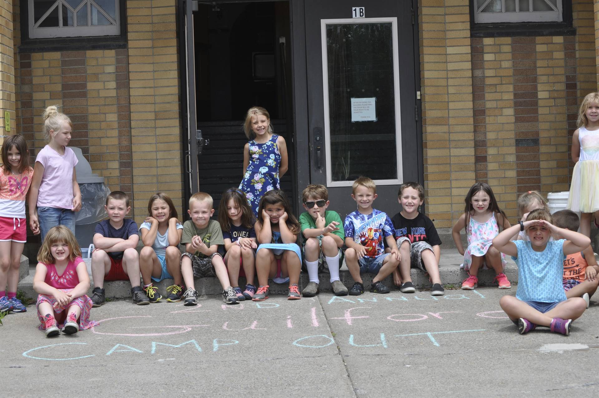 Students pose in front of building "Guilford Campout" sign.