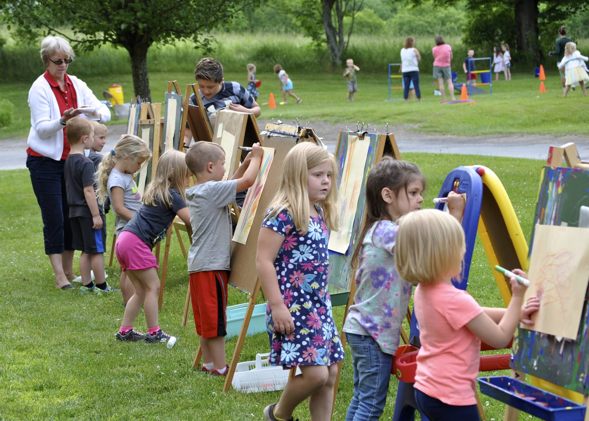 Art time as students draw on easels outdoors.
