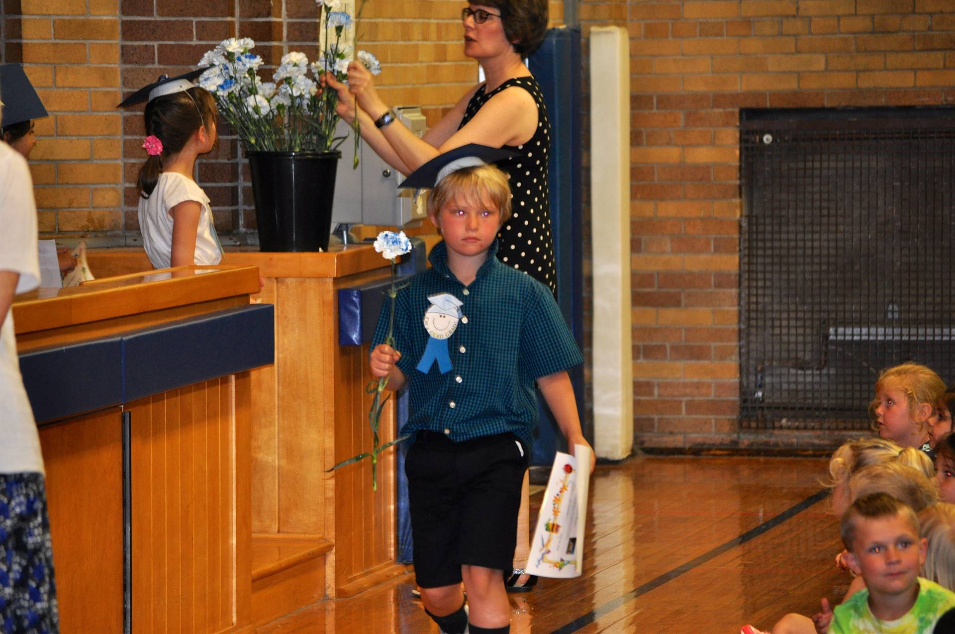 A student holds a carnation as he exits the stage.