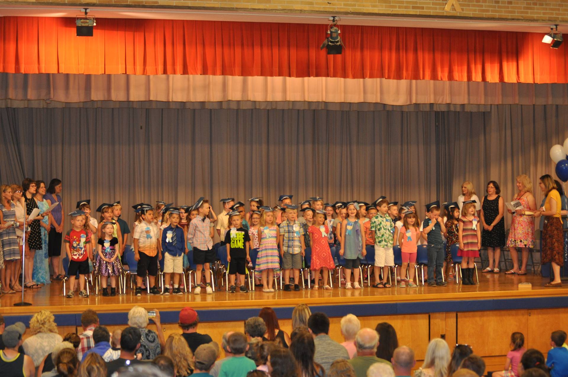 first graders sing a song on stage.