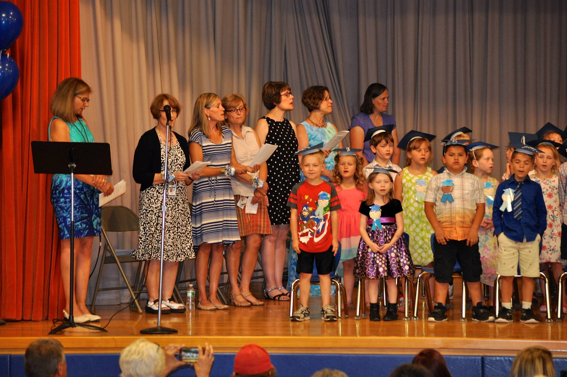 first graders and staff sing a song on stage.