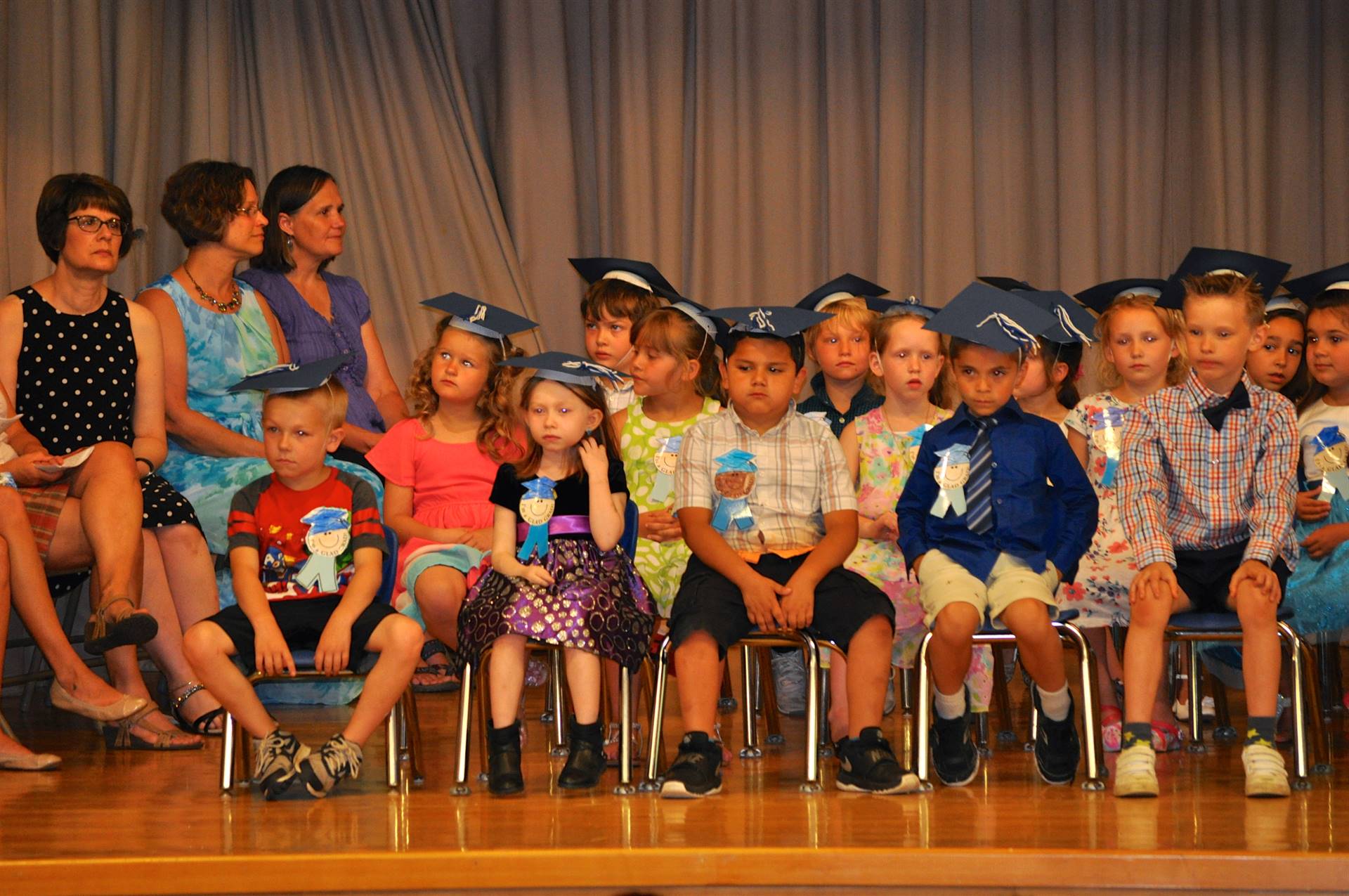 first graders sit on stage.