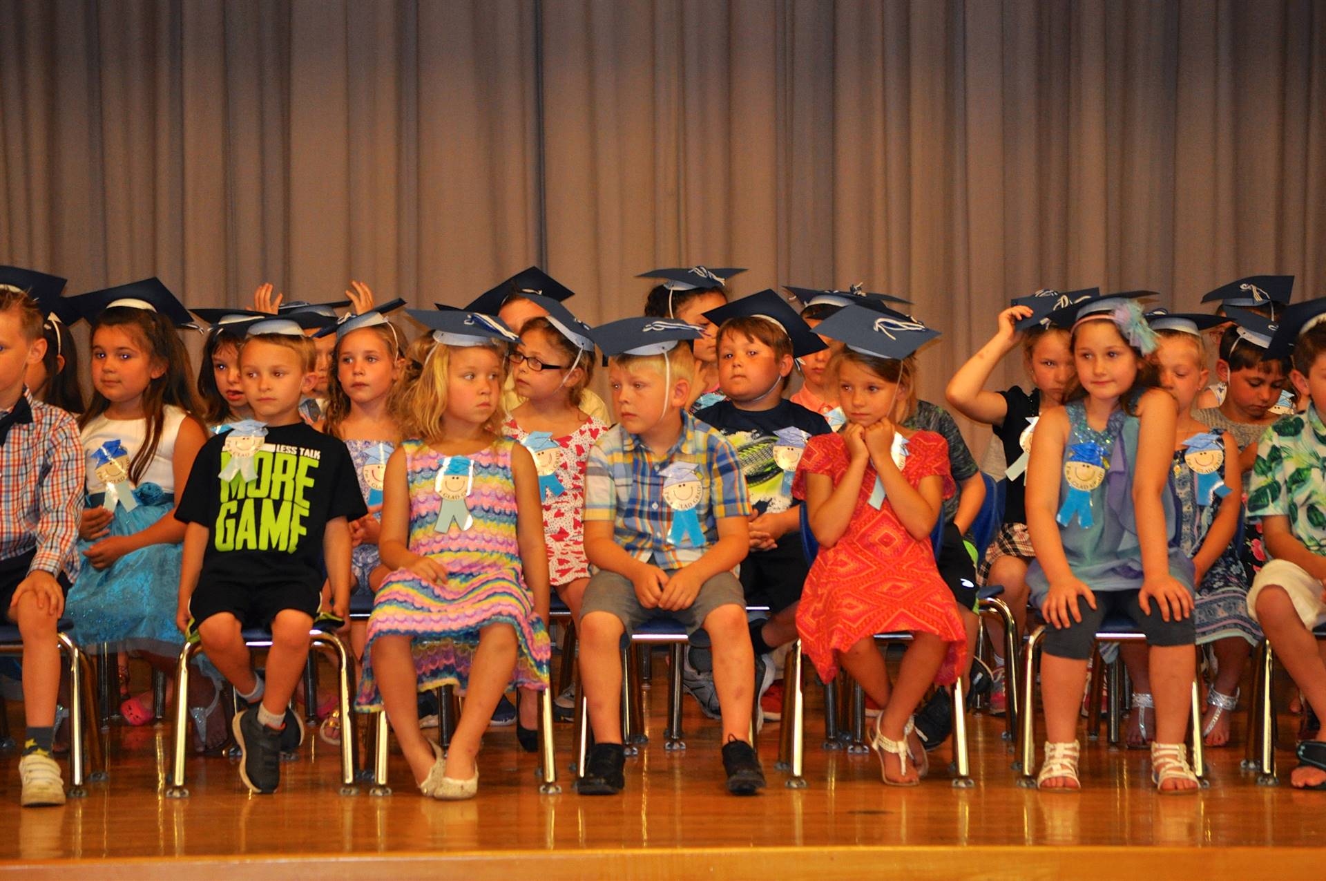 first graders sit  on stage.