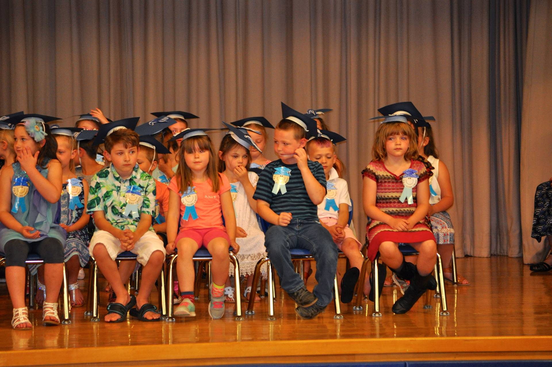 first graders sit on stage.