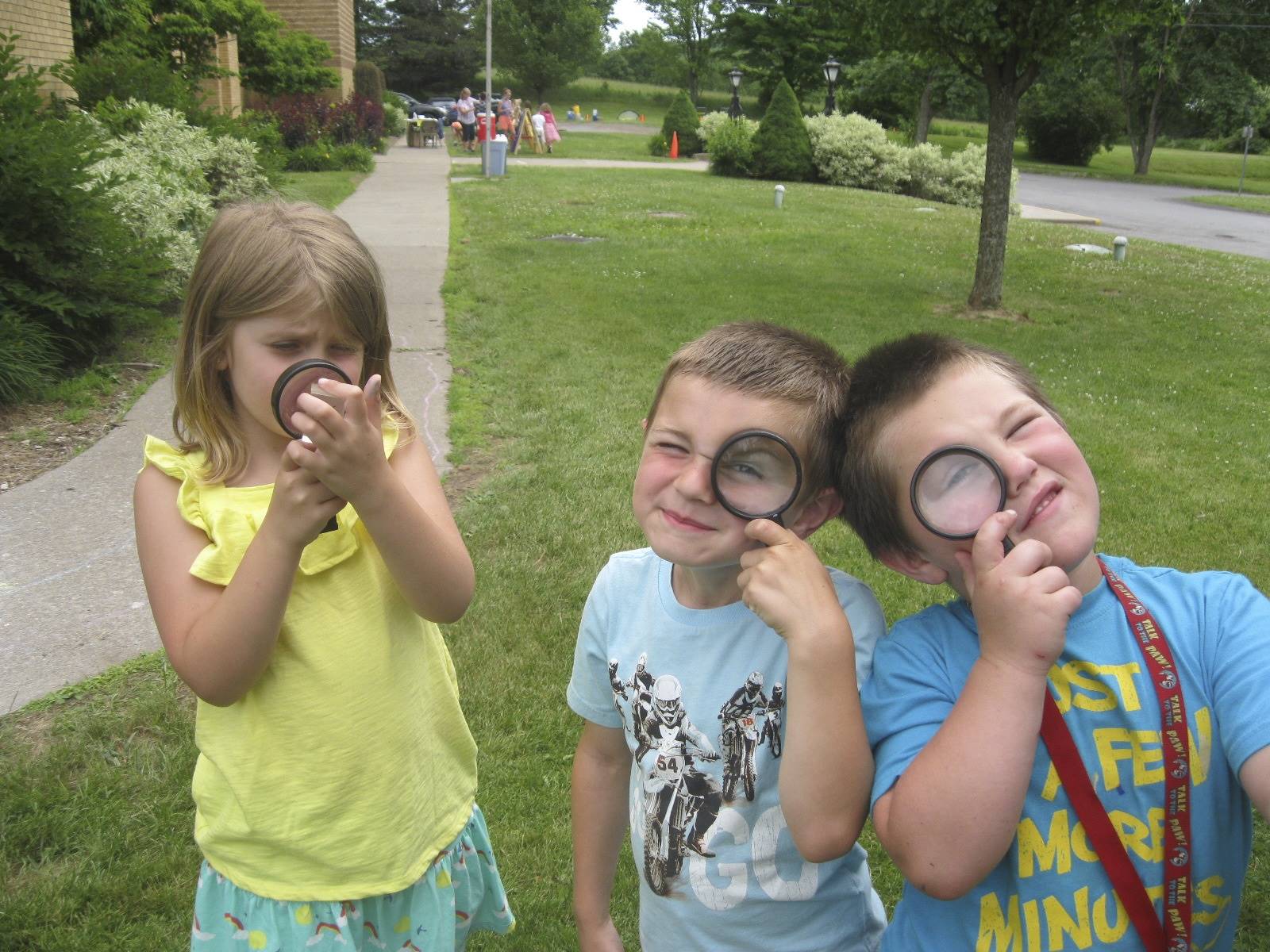 3 students look through magnifying glasses.