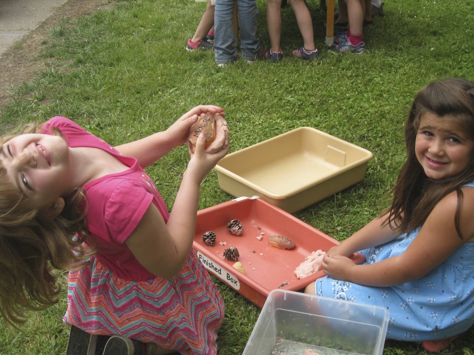 2 students smile as the play with bugs.