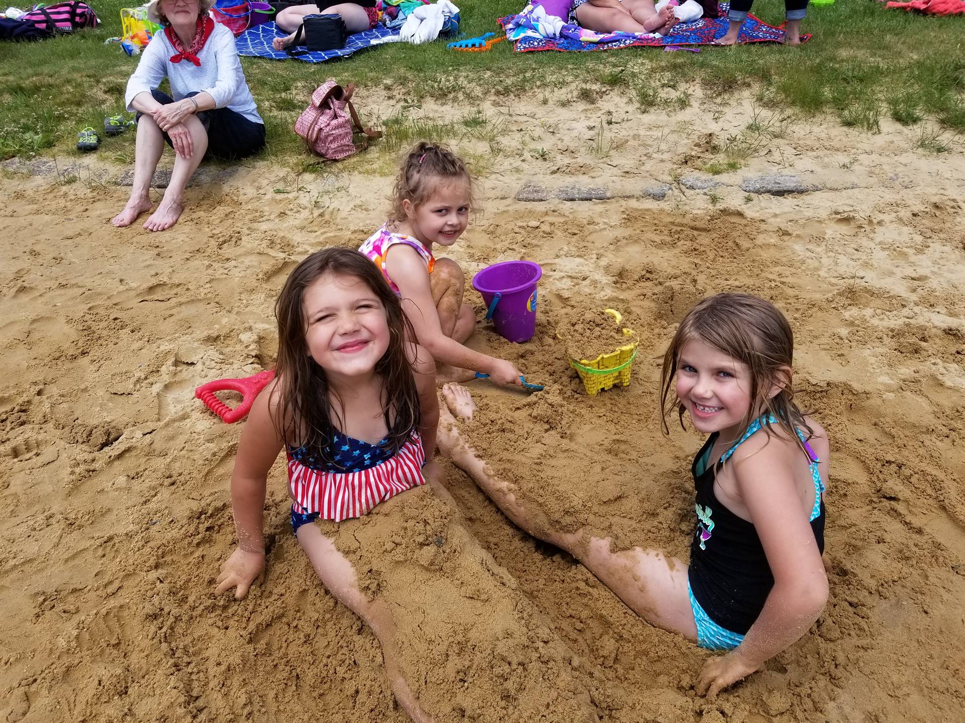 3 students create in the sand.