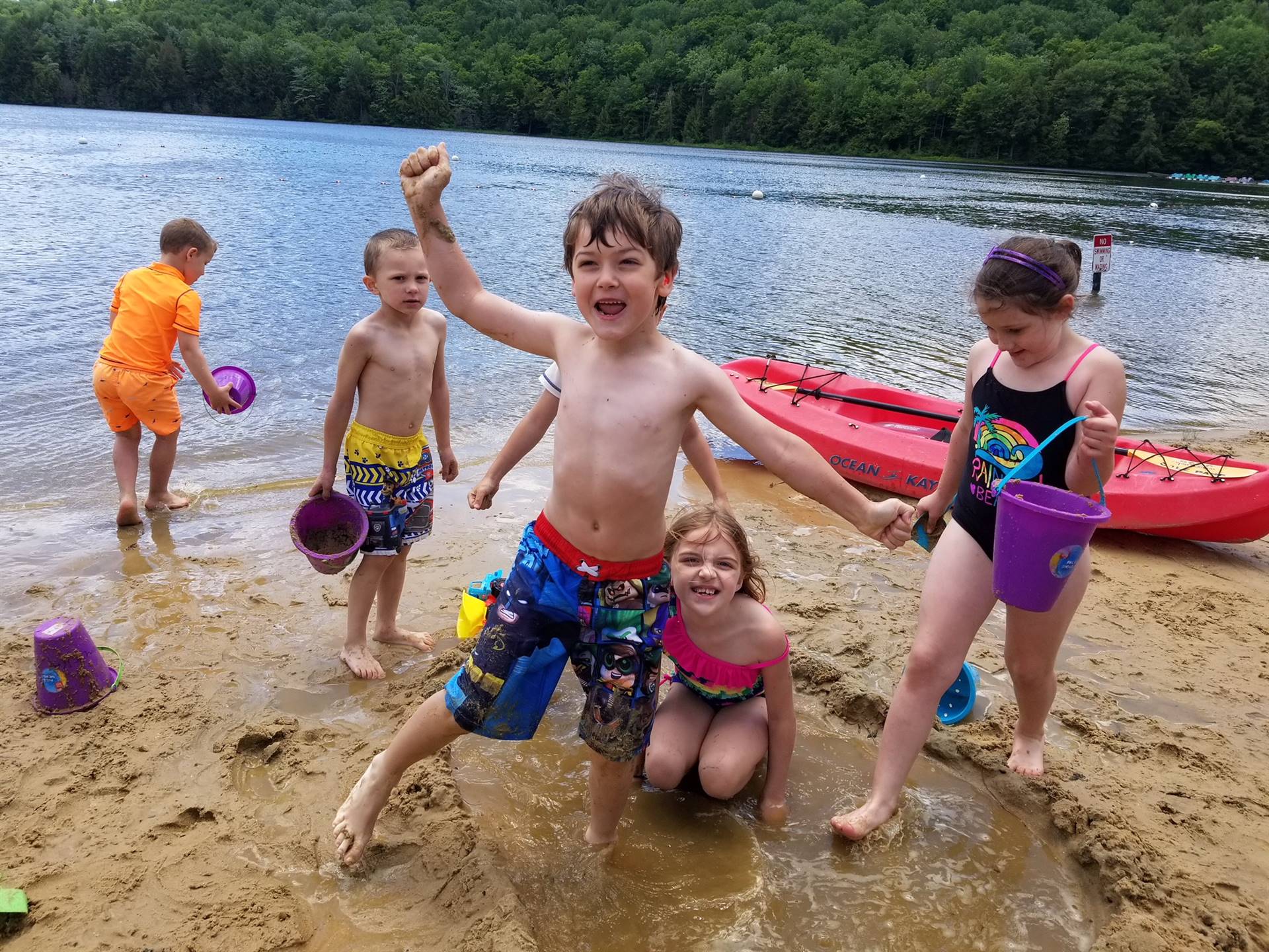 students do the superman pose on the beach.