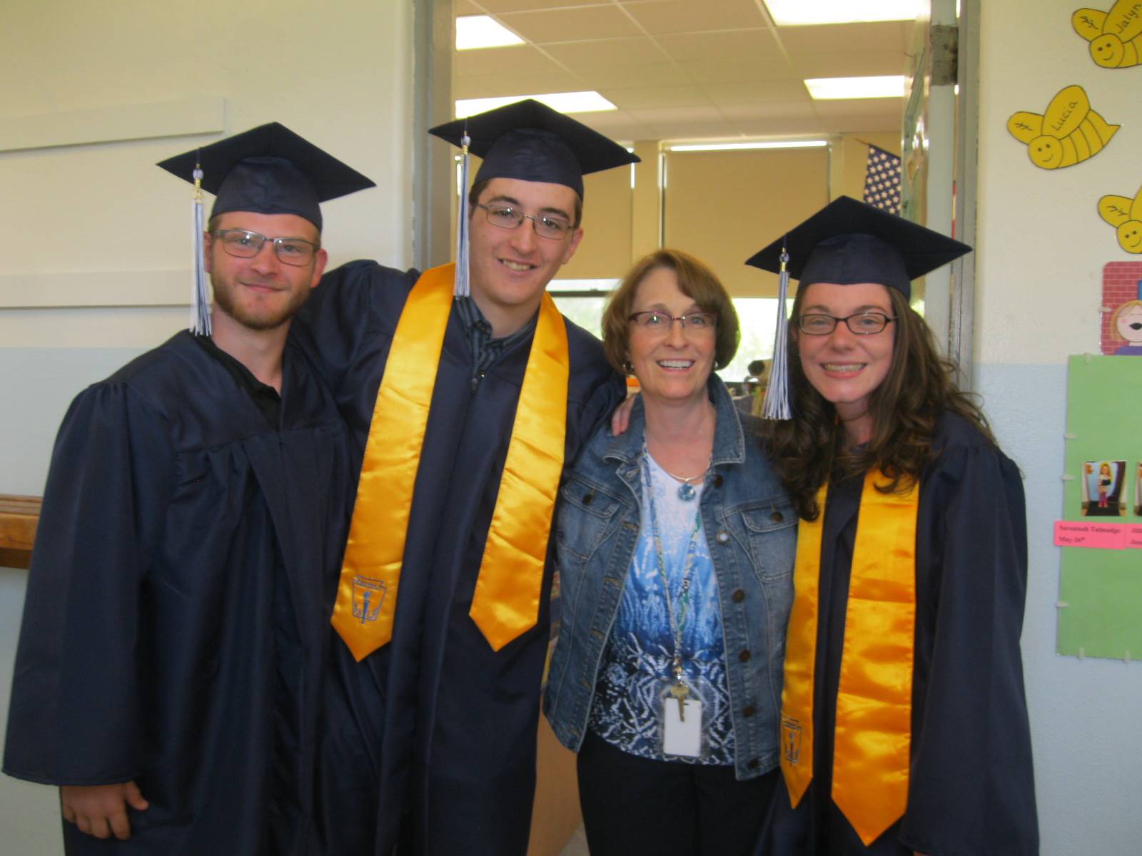 3 seniors pose with their first grade teacher