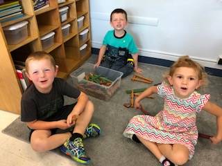 3 students play with lincoln logs.