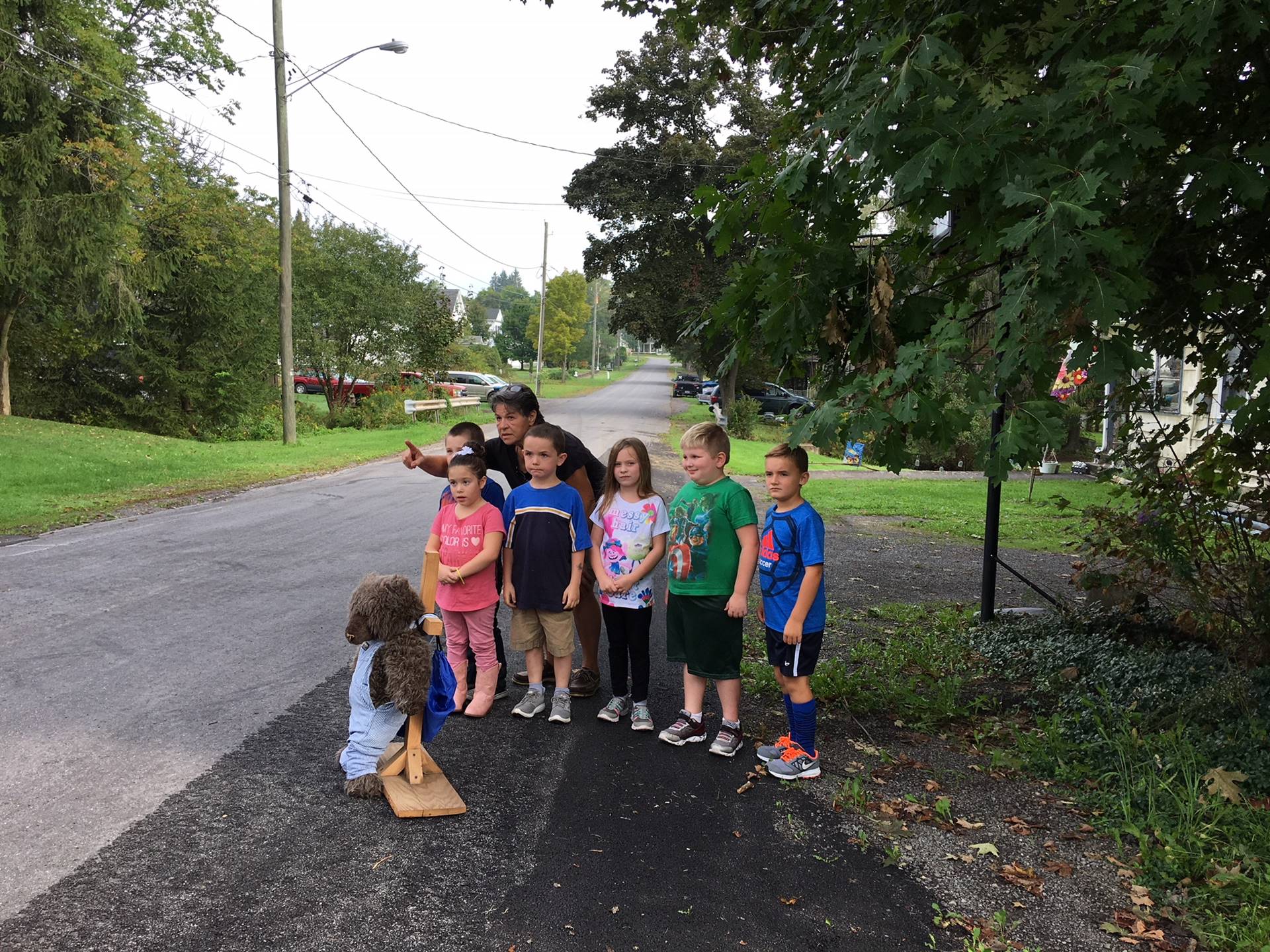 Bus driver shows students how to cross road.