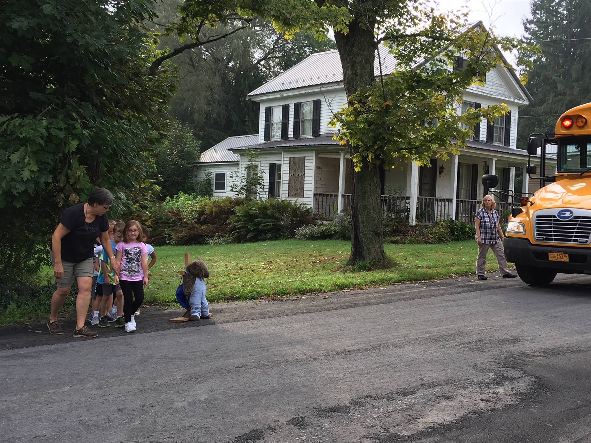 Bus driver leads students across road safely.