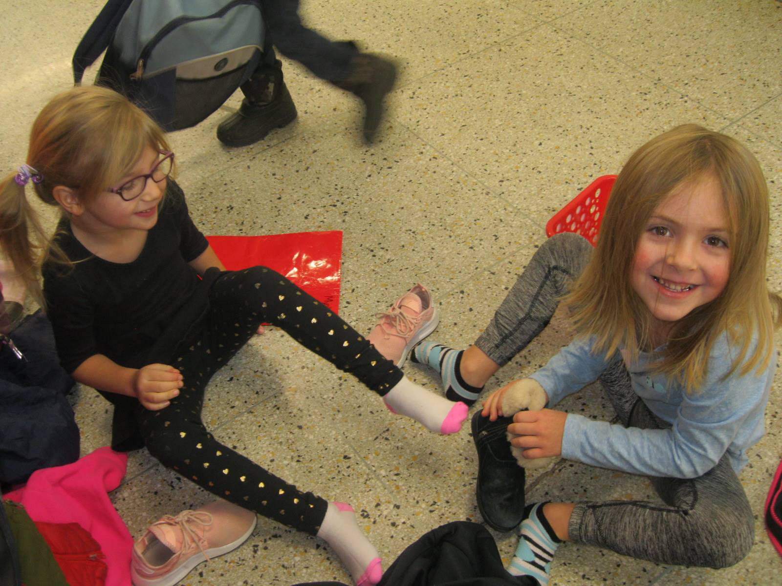 A student helps tie another student's shoes.